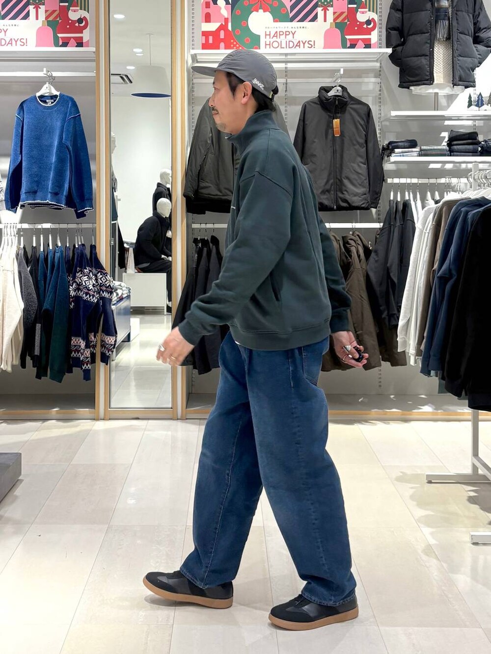 ベージュ系のスニーカー、ブルー系のデニムパンツ、グリーン系のスウェットを着用したメンズの冬コーディネートの2枚目の写真