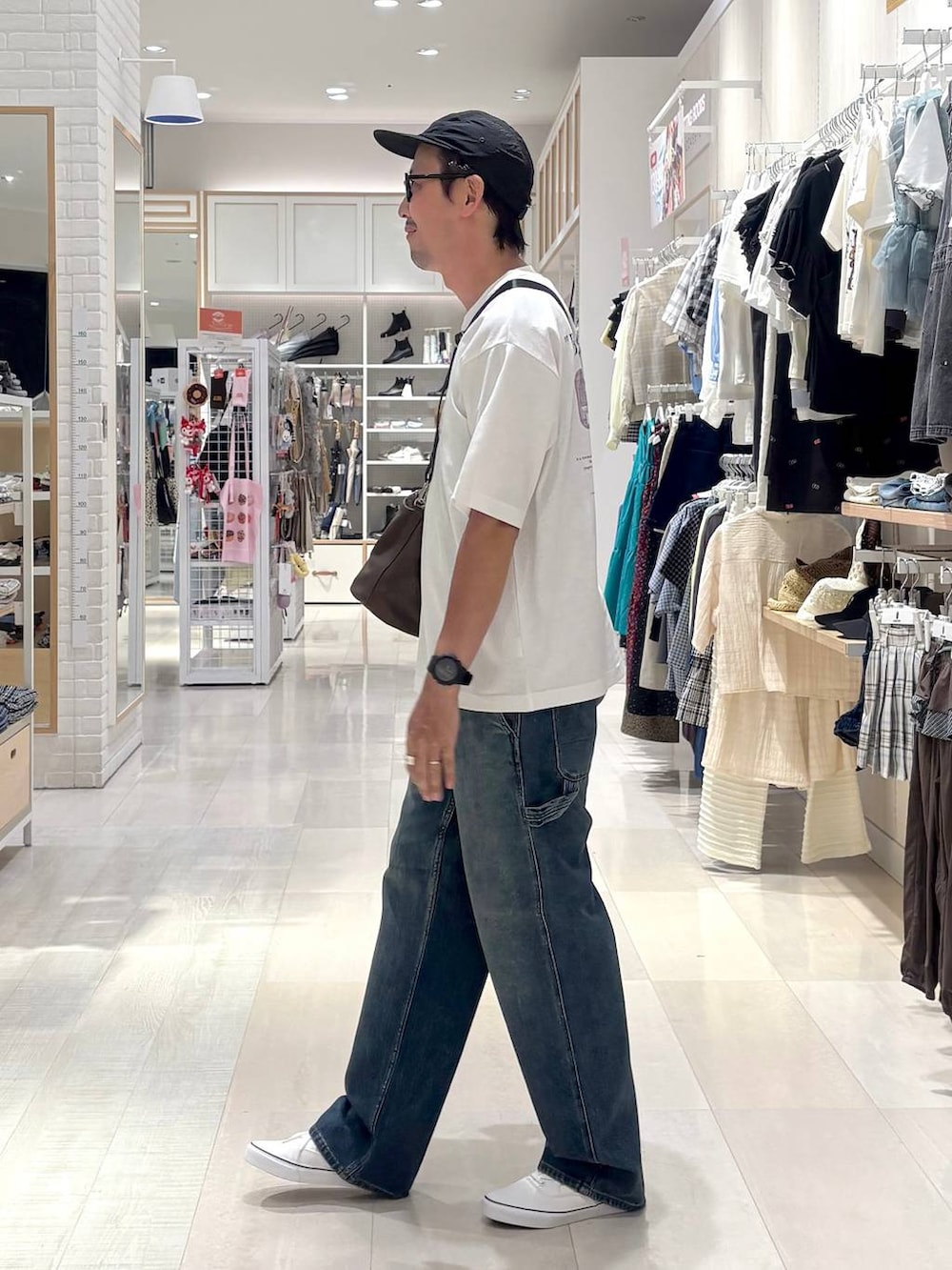 ブラウン系のショルダーバッグ、ブラック系のスニーカー、ブルー系のデニムパンツを着用したメンズの秋コーディネートの2枚目の写真