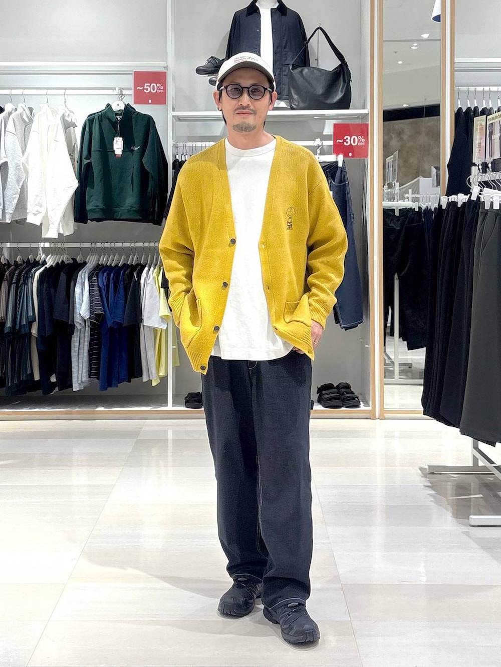 ブルー系のデニムパンツ、イエロー系のカーディガン/ボレロ、ブラック系のサングラスを着用したメンズの秋コーディネートの2枚目の写真