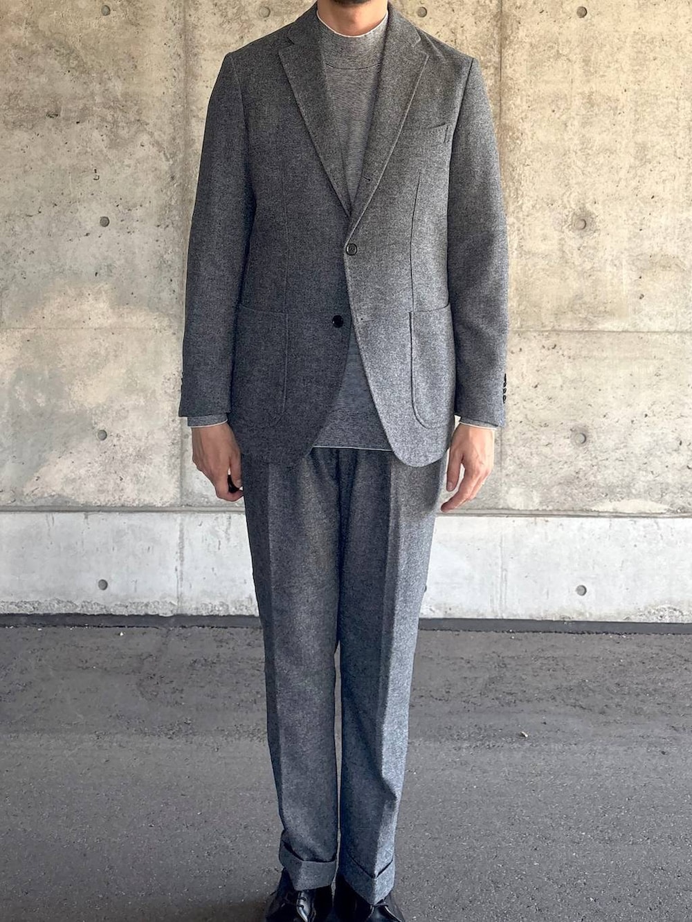 グレー系のテーラードジャケット、グレー系のスラックス、グレー系のニット/セーターを着用したメンズの秋コーディネートの2枚目の写真