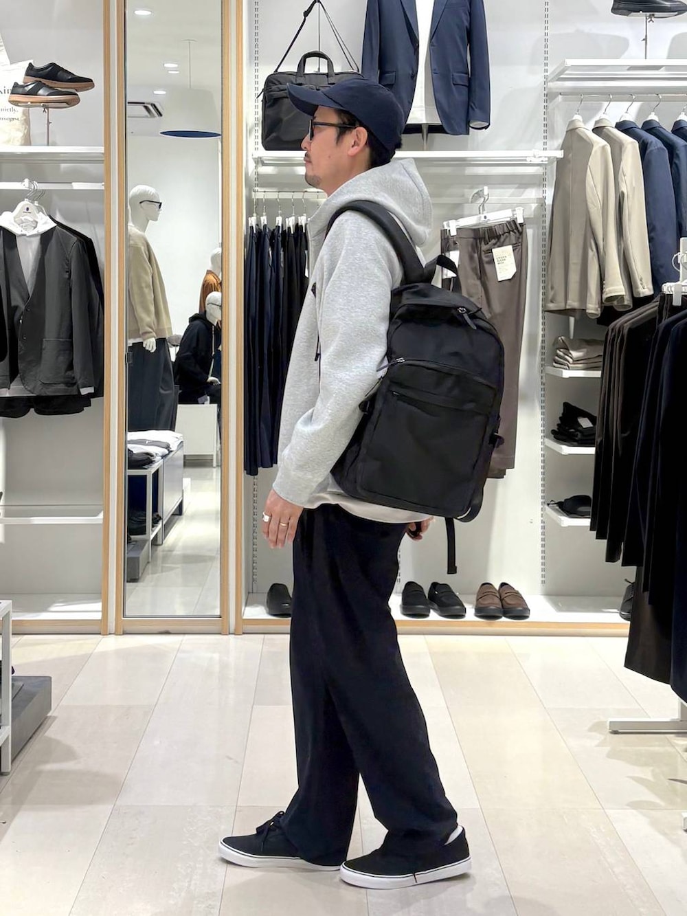 ブラック系のバックパック/リュック、ベージュ系のTシャツ/カットソー、グレー系のパーカーを着用したメンズの春コーディネートの2枚目の写真