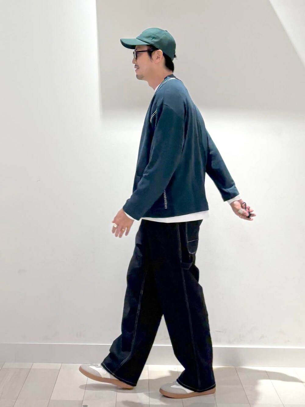 ベージュ系のスニーカー、ブルー系のデニムパンツ、グリーン系のカーディガン/ボレロを着用したメンズの秋コーディネートの2枚目の写真