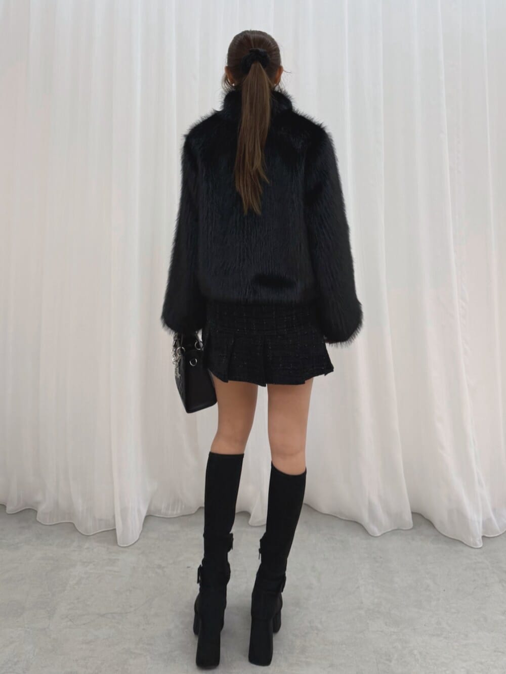 ブラック系のブーツ、ブラック系のブルゾン、ブラック系のハンドバッグを着用したレディースの冬コーディネートの4枚目の写真