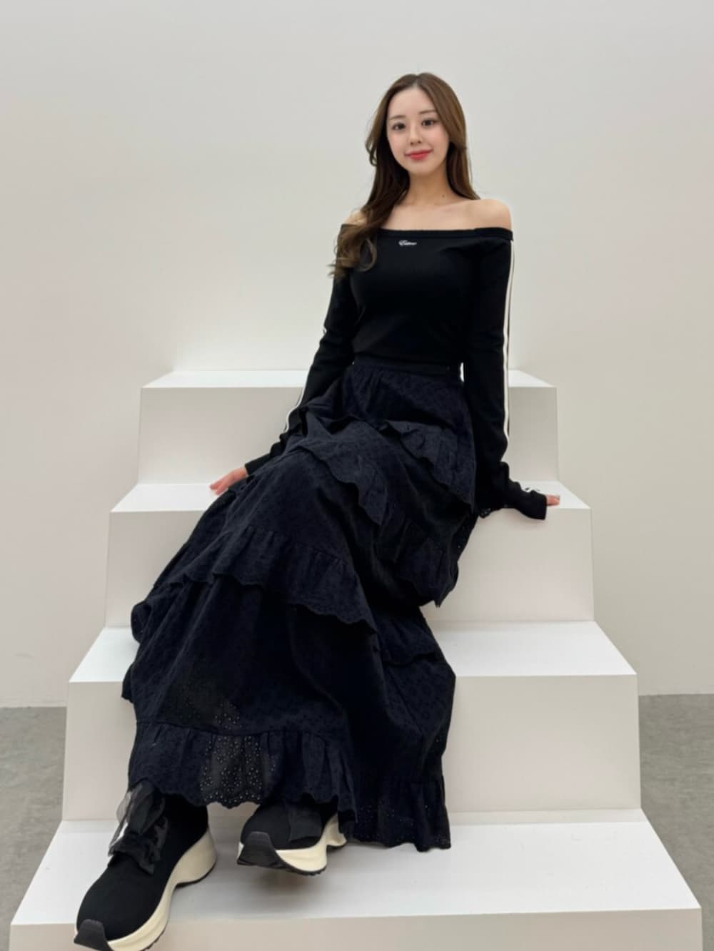 ホワイト系のブーツ、ブラック系のスカート、ブラック系のTシャツ/カットソーを着用したレディースの春コーディネートの2枚目の写真