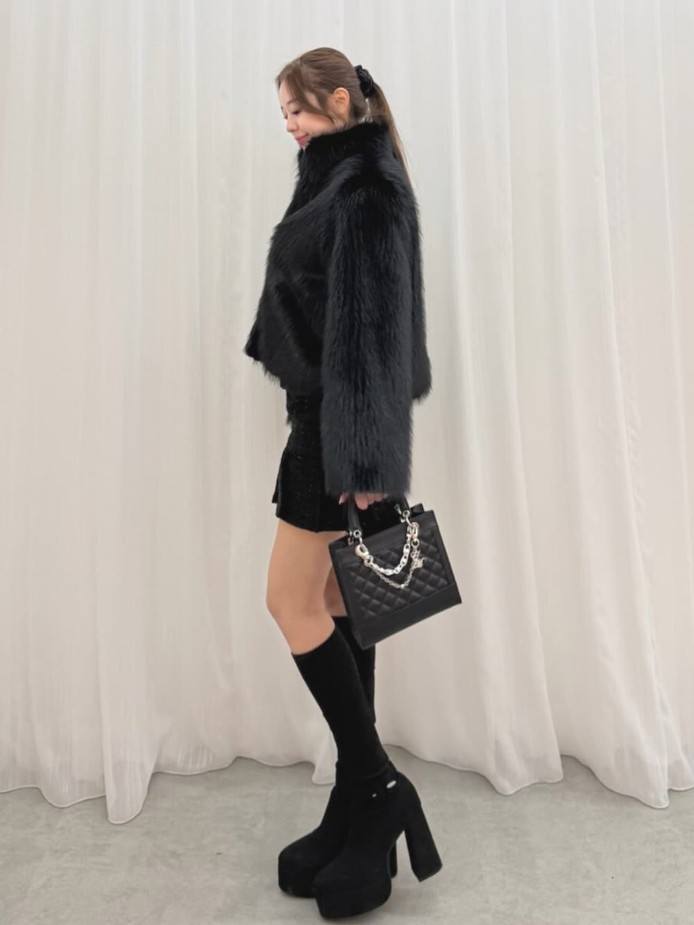 ブラック系のブーツ、ブラック系のブルゾン、ブラック系のハンドバッグを着用したレディースの冬コーディネートの2枚目の写真