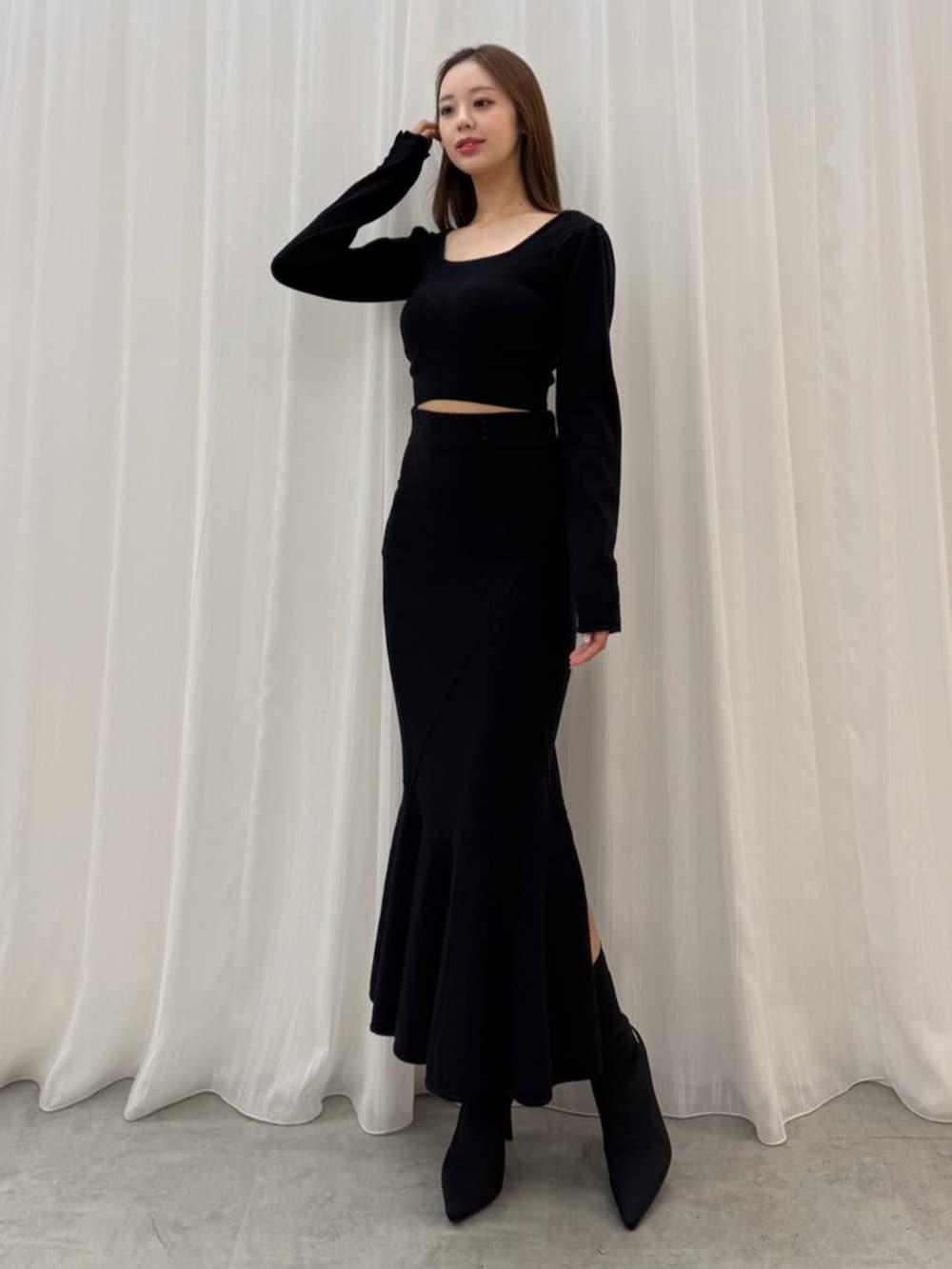 ブラック系のブーツ、ブラック系のスカート、ブラック系のニット/セーターを着用したレディースの秋コーディネートの2枚目の写真