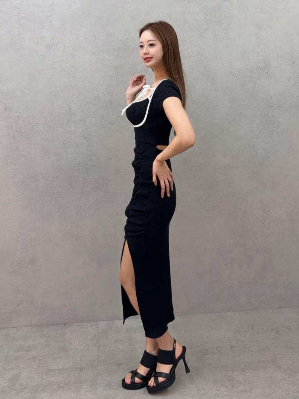 ホワイト系のサンダル、ブラック系のワンピースを着用したレディースの春コーディネートの2枚目の写真