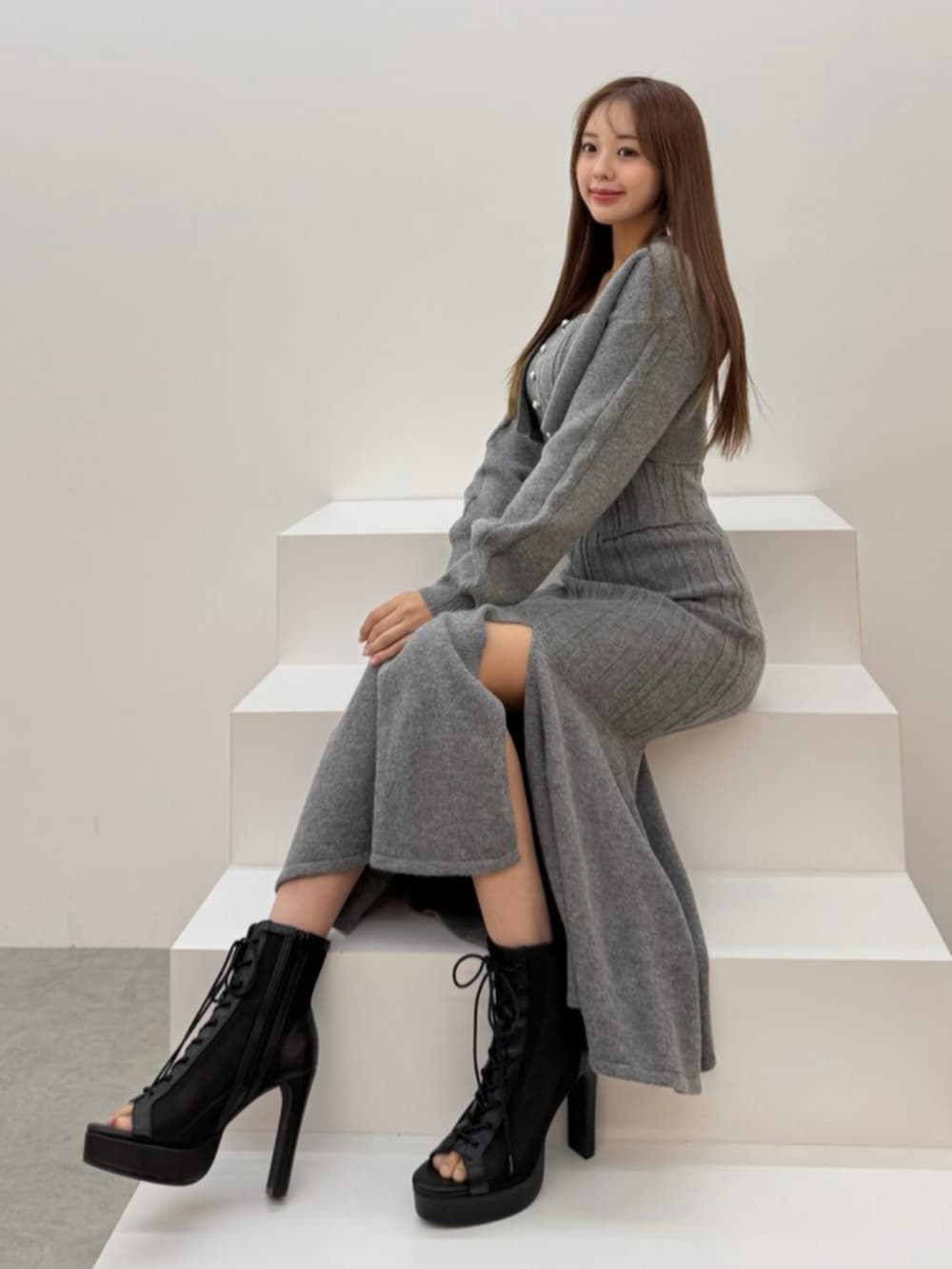 ブラック系のサンダル、グレー系のニット/セーター、グレー系のスカートを着用したレディースの冬コーディネートの4枚目の写真