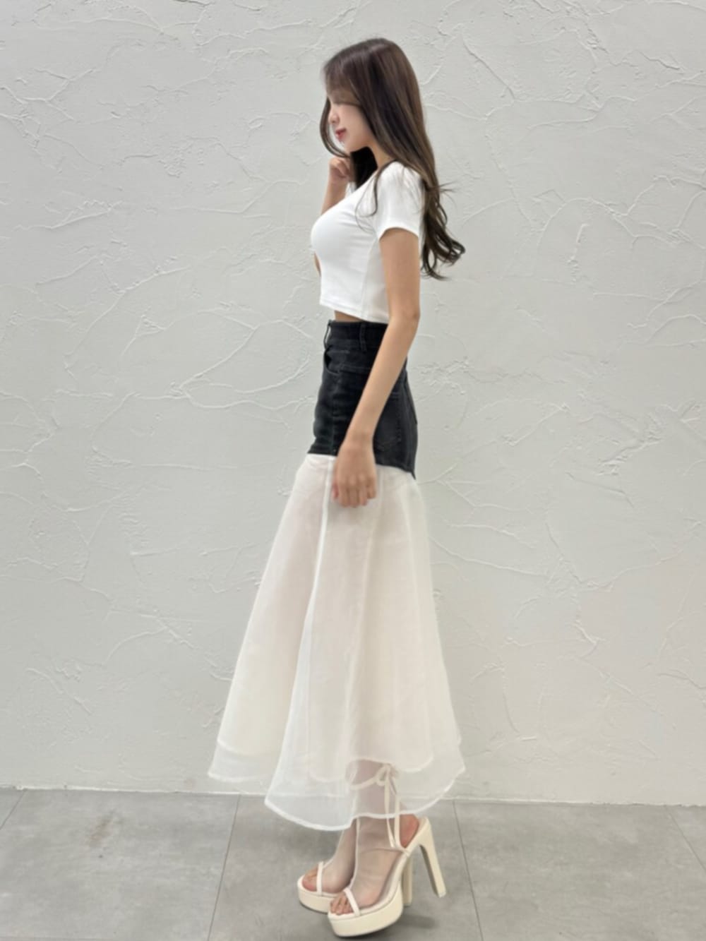 ホワイト系のサンダル、ホワイト系のTシャツ/カットソー、ブラック系のデニムスカートを着用したレディースの夏コーディネートの2枚目の写真