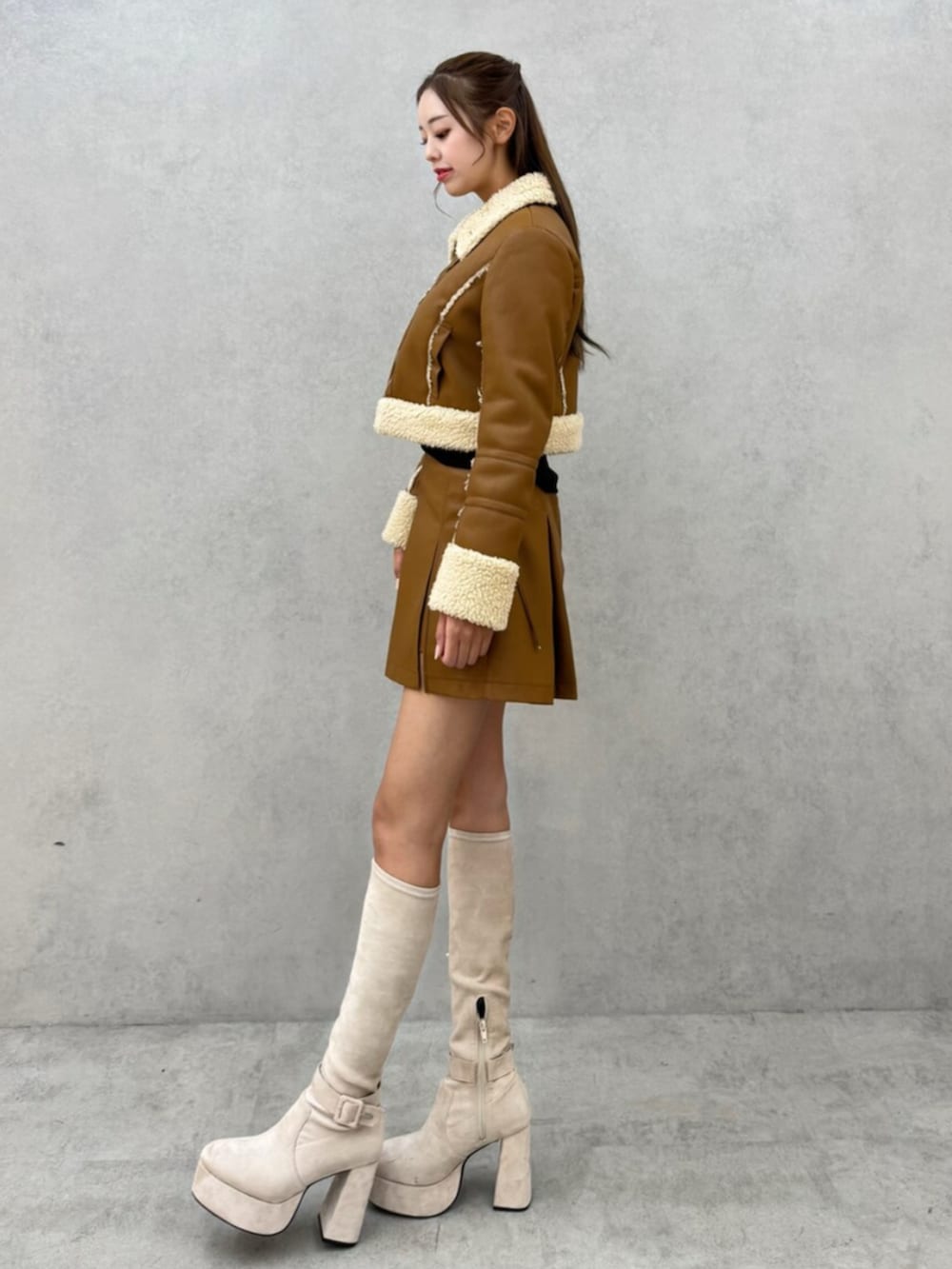 ホワイト系のブーツ、ブラウン系のスカート、ブラウン系のブルゾンを着用したレディースの秋コーディネートの2枚目の写真