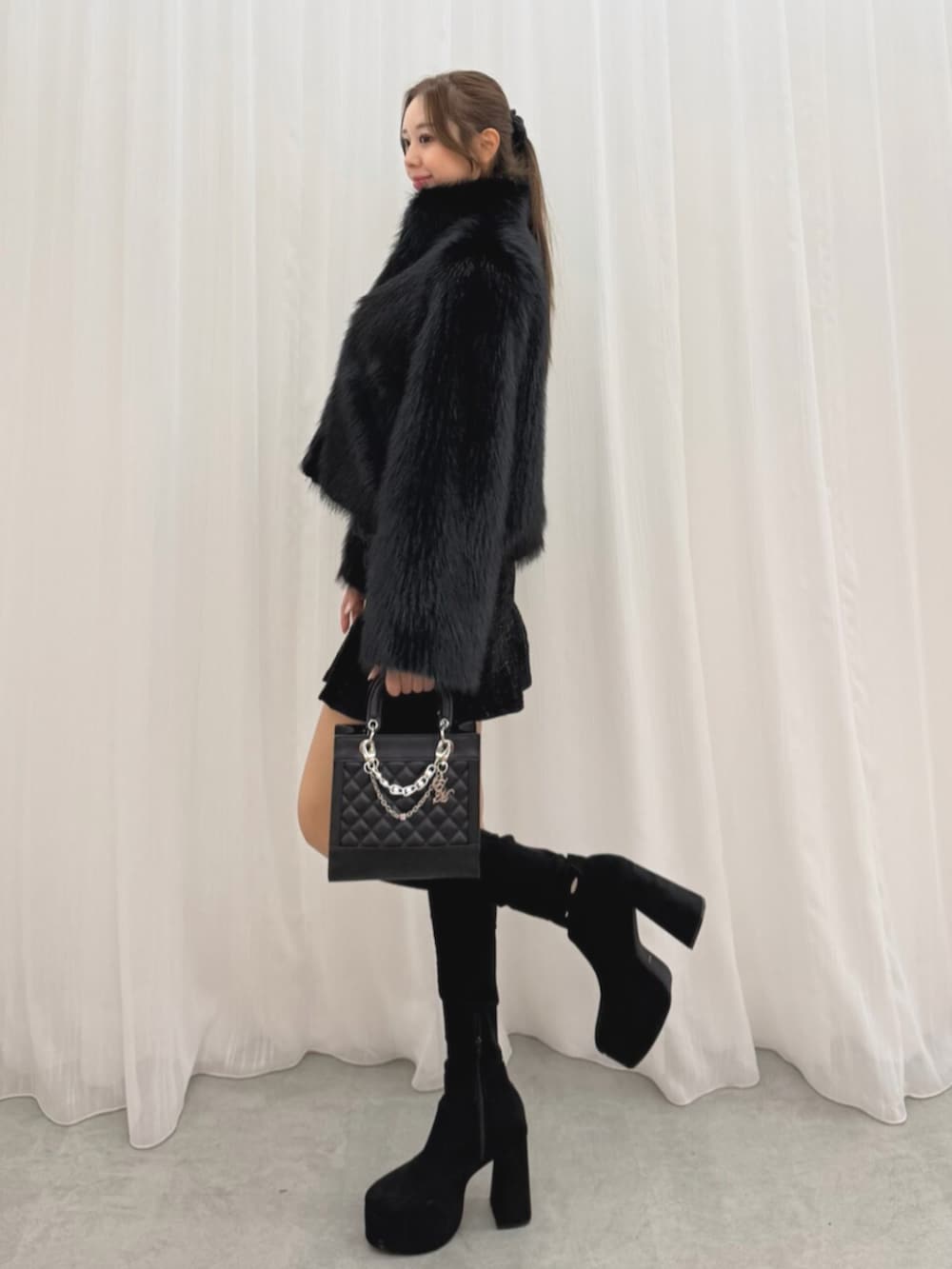 ブラック系のブーツ、ブラック系のブルゾン、ブラック系のハンドバッグを着用したレディースの冬コーディネートの3枚目の写真