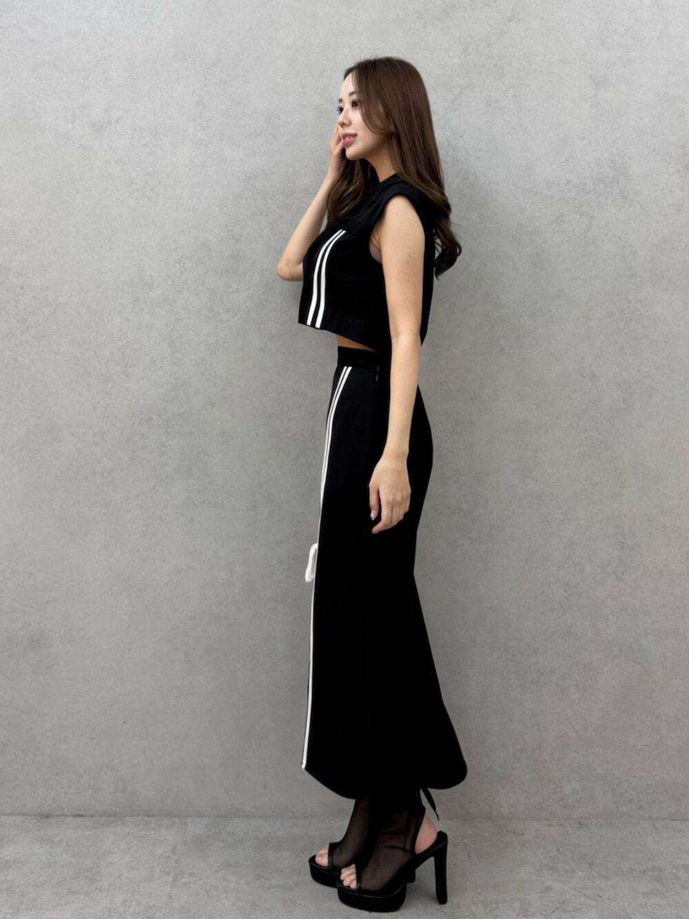 ブラック系のサンダル、ブラック系のベスト、ブラック系のスカートを着用したレディースの春コーディネートの2枚目の写真