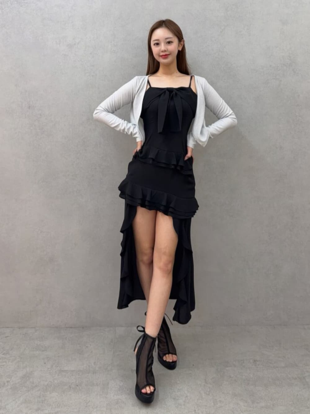 ホワイト系のブーツ、ホワイト系のカーディガン/ボレロ、ブラック系のワンピースを着用したレディースの春コーディネートの2枚目の写真