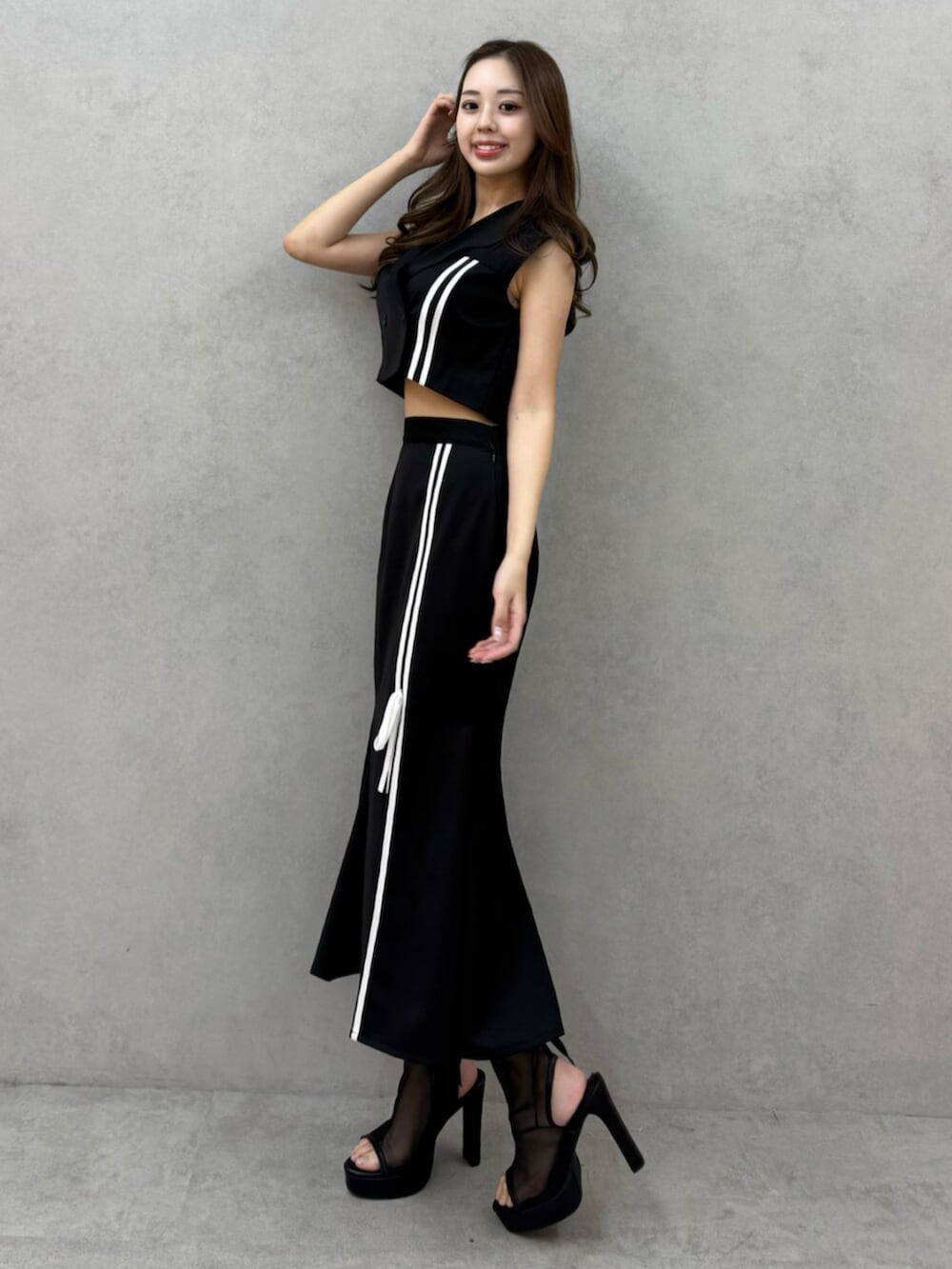 ブラック系のサンダル、ブラック系のベスト、ブラック系のスカートを着用したレディースの春コーディネートの3枚目の写真