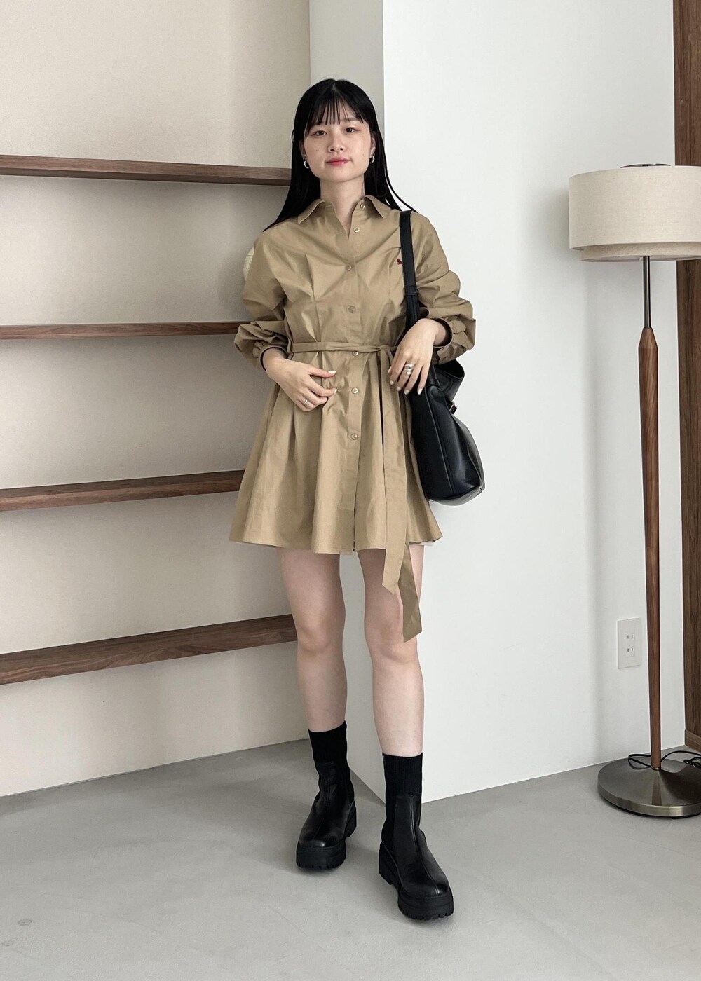 ブラック系のブーツ、ブラック系のショルダーバッグ、ベージュ系のワンピースを着用したレディースの夏コーディネートの2枚目の写真