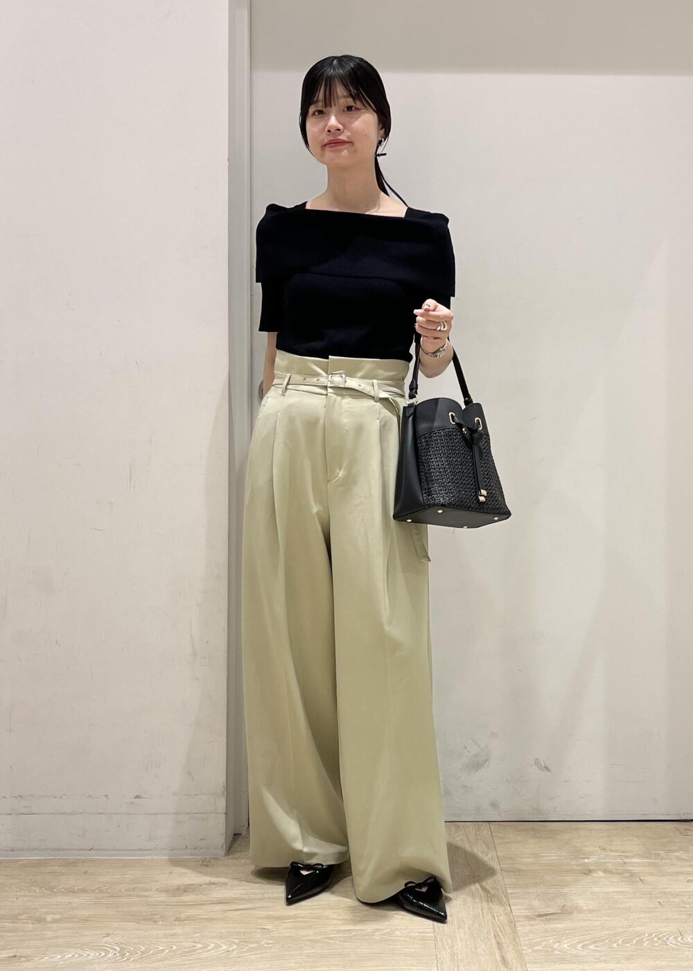 ブラック系のパンプス、ブラック系のショルダーバッグ、グリーン系のスラックスを着用したレディースの夏コーディネートの2枚目の写真