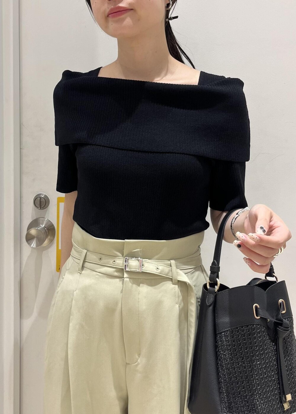 ブラック系のパンプス、ブラック系のショルダーバッグ、グリーン系のスラックスを着用したレディースの夏コーディネートの5枚目の写真