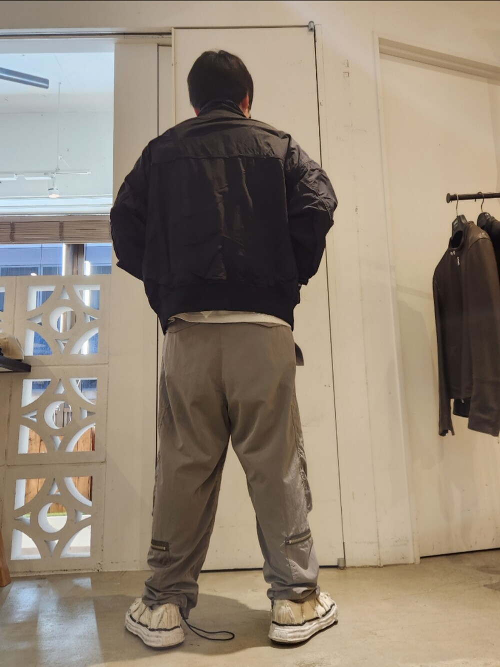 ブラック系のミリタリージャケット、グレー系のカーゴパンツ、ホワイト系のスニーカーを着用したメンズの冬コーディネートの2枚目の写真