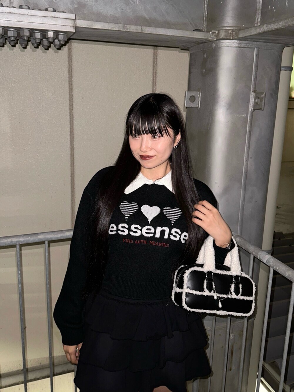 ブラック系のスカート、ブラック系のニット/セーター、ブラック系のハンドバッグを着用したレディースの秋コーディネートの4枚目の写真