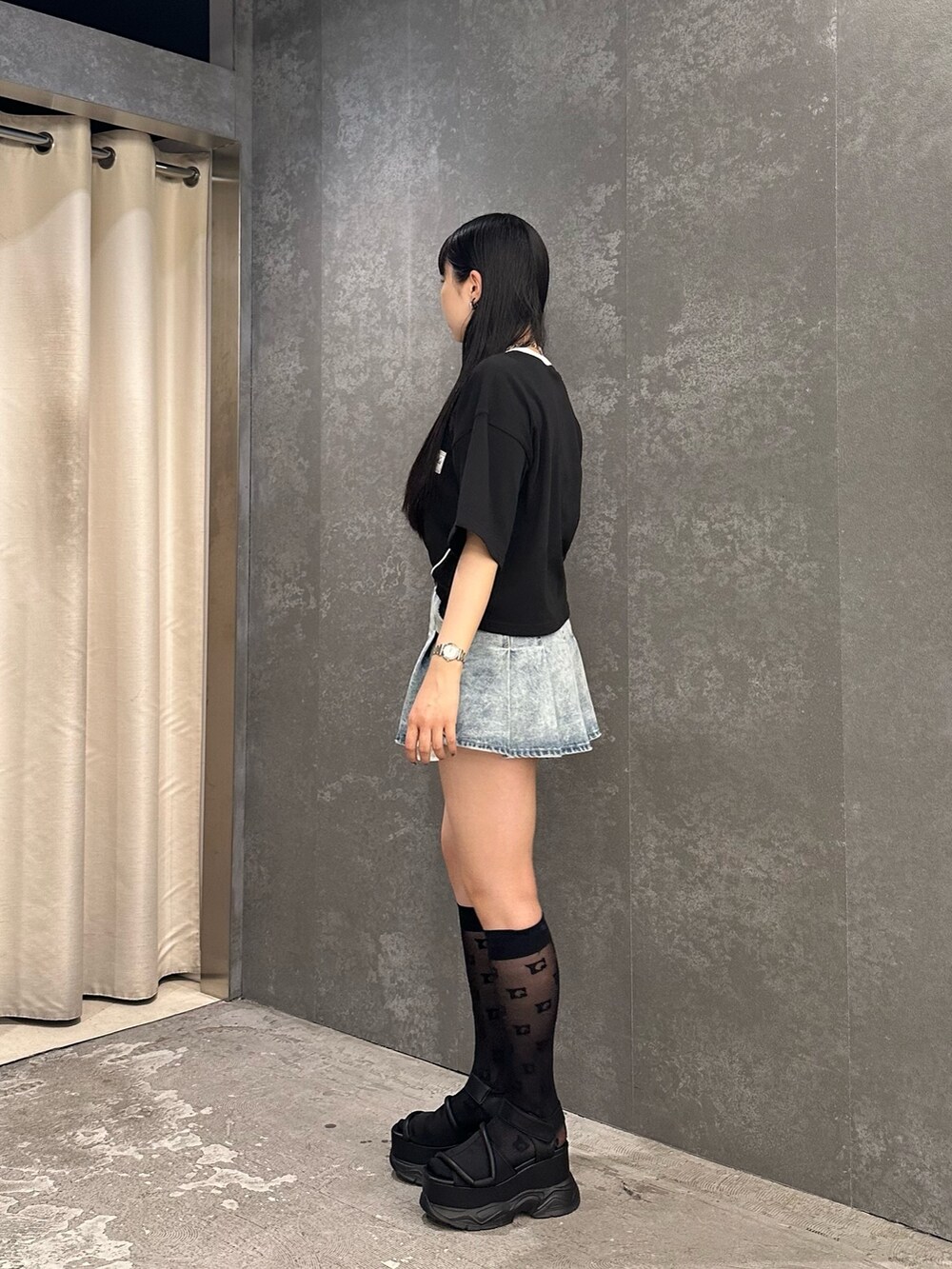 ブルー系のデニムスカート、ブラック系のTシャツ/カットソー、ブラック系のサンダルを着用したレディースの春コーディネートの3枚目の写真