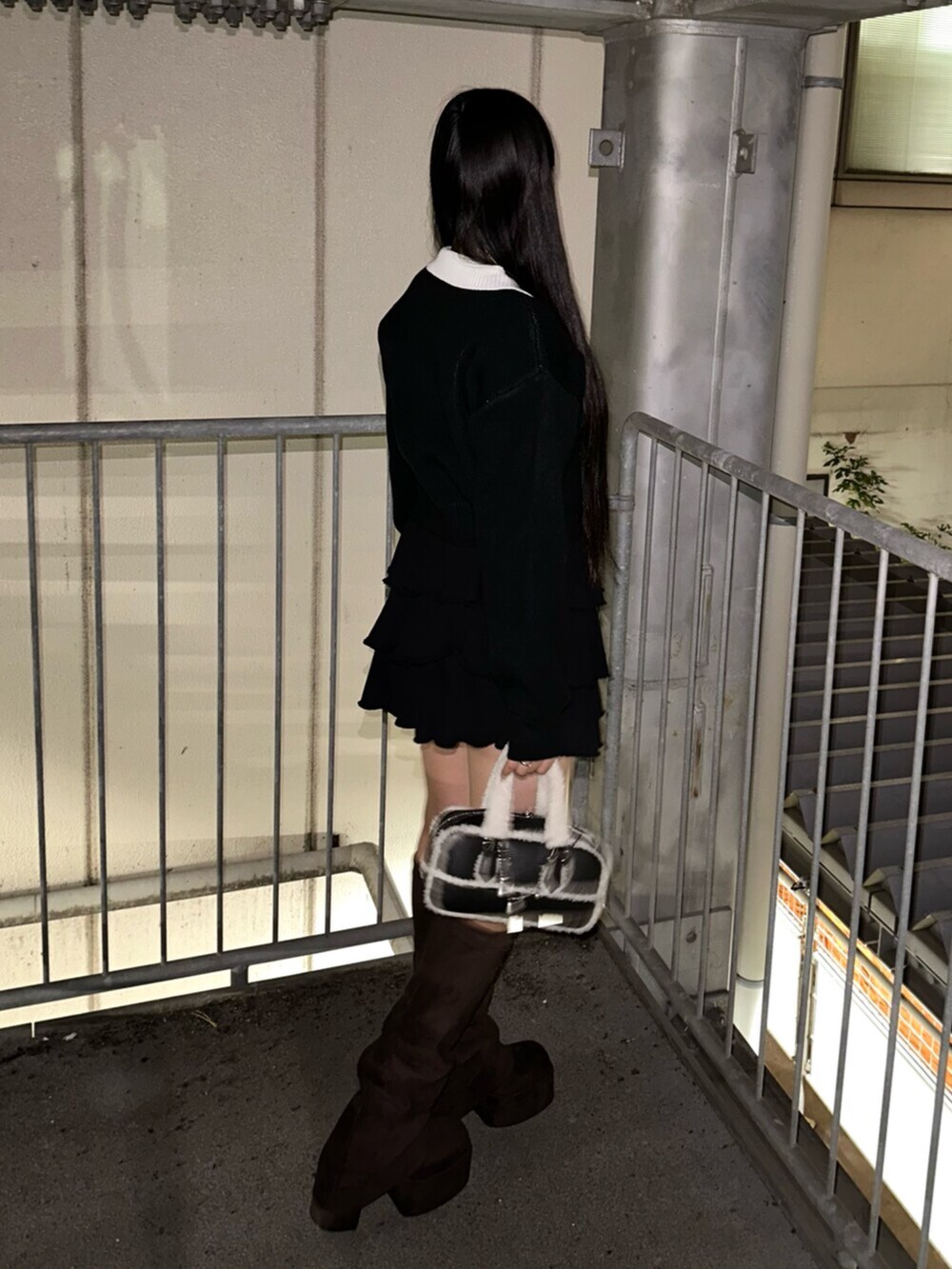 ブラック系のスカート、ブラック系のニット/セーター、ブラック系のハンドバッグを着用したレディースの秋コーディネートの3枚目の写真