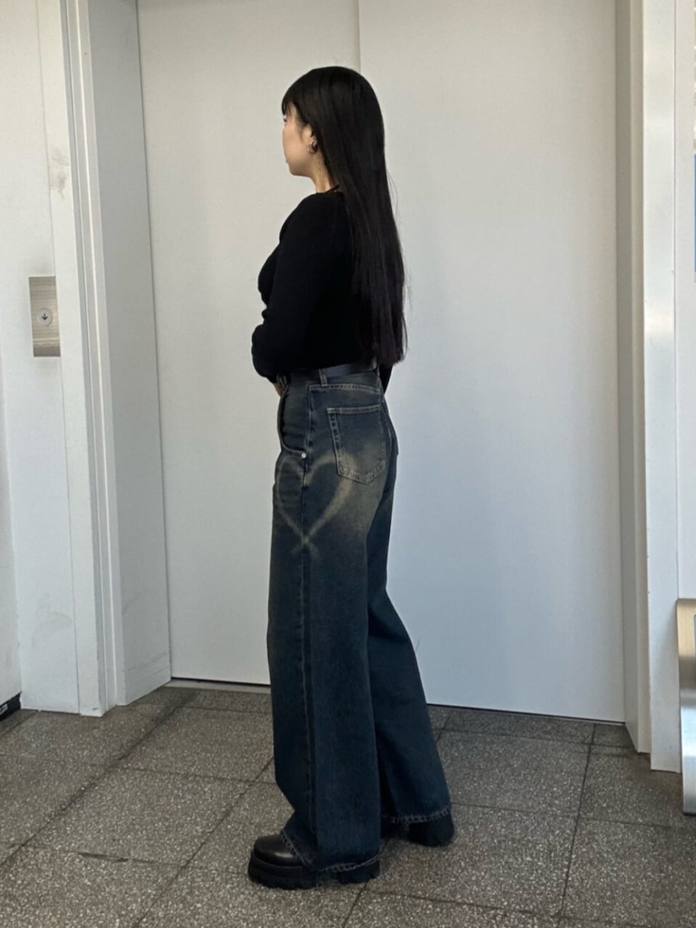 ブラック系のブーツ、ブルー系のデニムパンツ、ブラック系のニット/セーターを着用したレディースの冬コーディネートの3枚目の写真