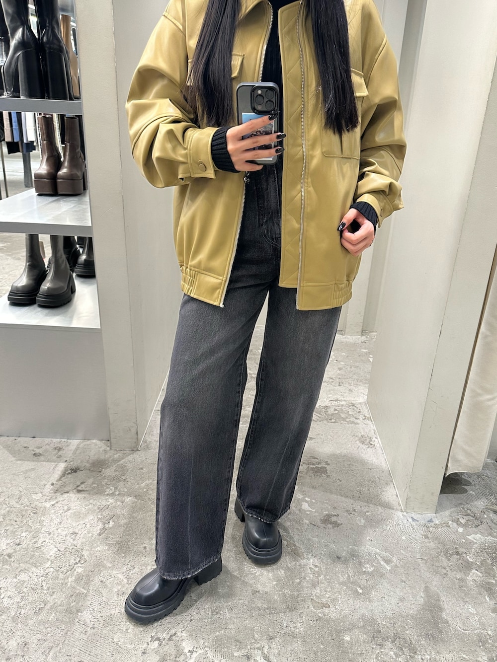 ブラック系のデニムパンツ、イエロー系のブルゾン、ブラック系のニット/セーターを着用したレディースの冬コーディネートの6枚目の写真