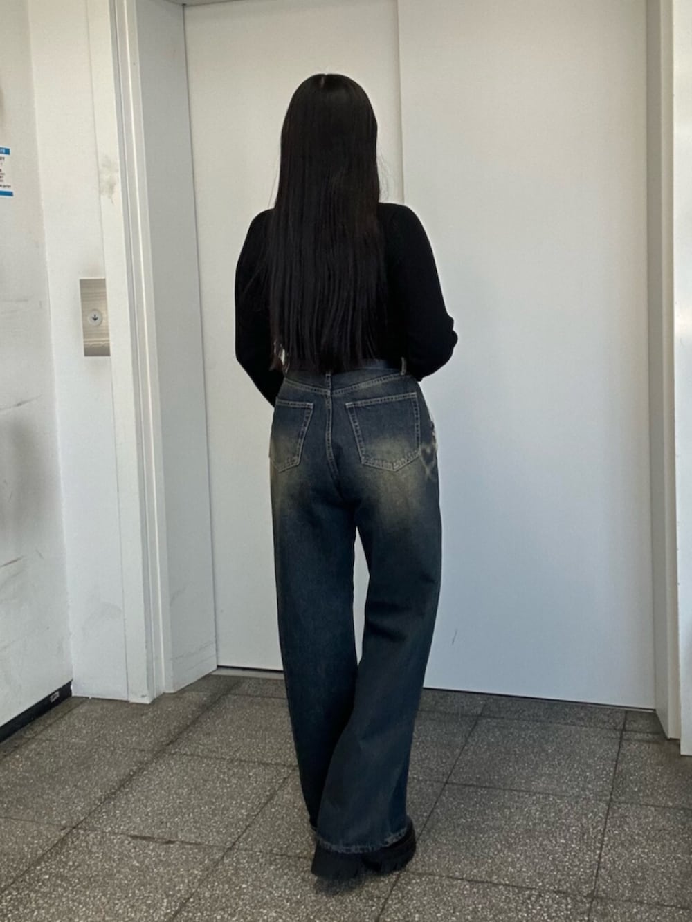 ブラック系のブーツ、ブルー系のデニムパンツ、ブラック系のニット/セーターを着用したレディースの冬コーディネートの5枚目の写真