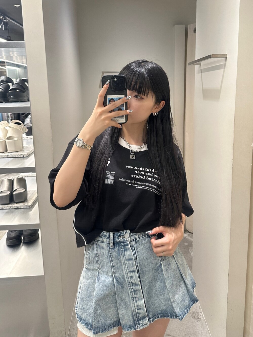 ブルー系のデニムスカート、ブラック系のTシャツ/カットソー、ブラック系のサンダルを着用したレディースの春コーディネートの4枚目の写真