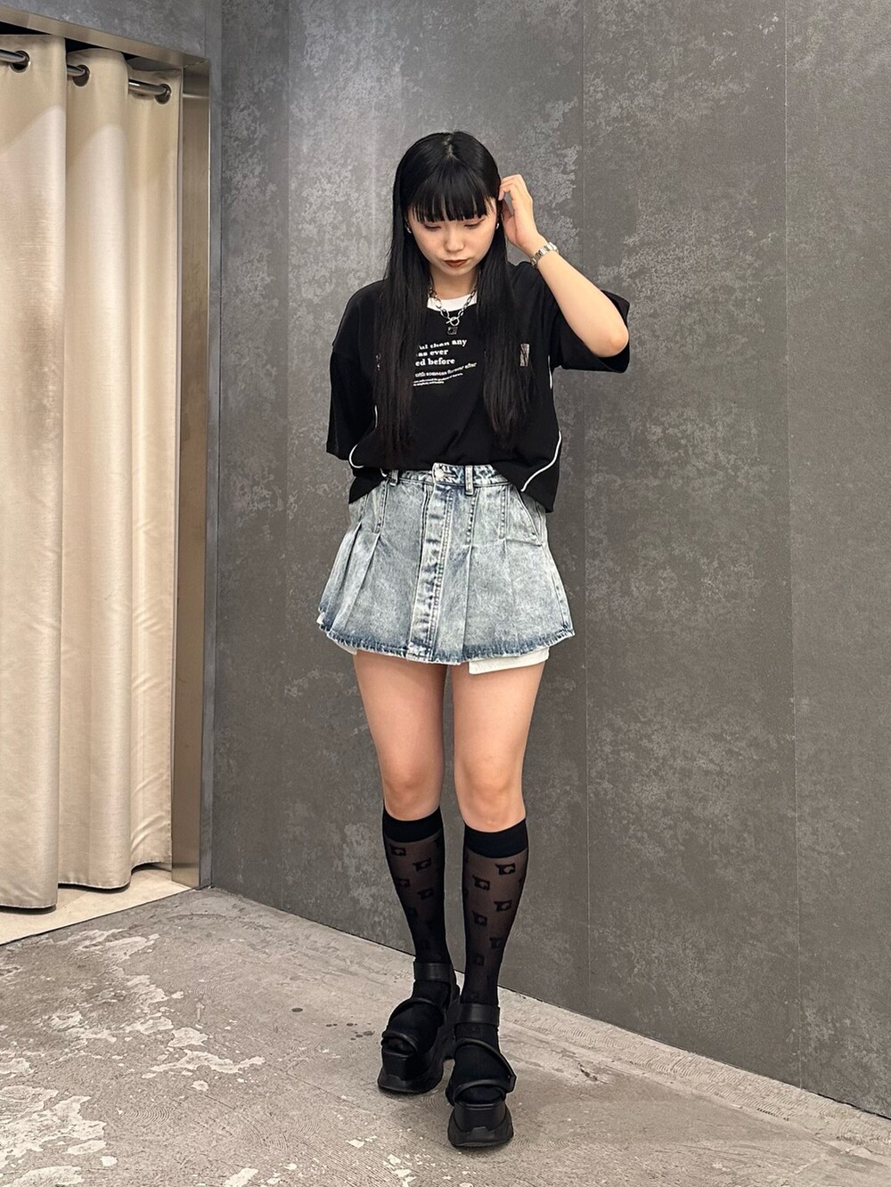 ブルー系のデニムスカート、ブラック系のTシャツ/カットソー、ブラック系のサンダルを着用したレディースの春コーディネートの2枚目の写真