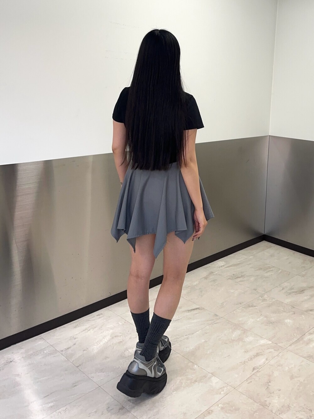 シルバー系のスニーカー、グレー系のスカート、ブラック系のTシャツ/カットソーを着用したレディースの春コーディネートの4枚目の写真