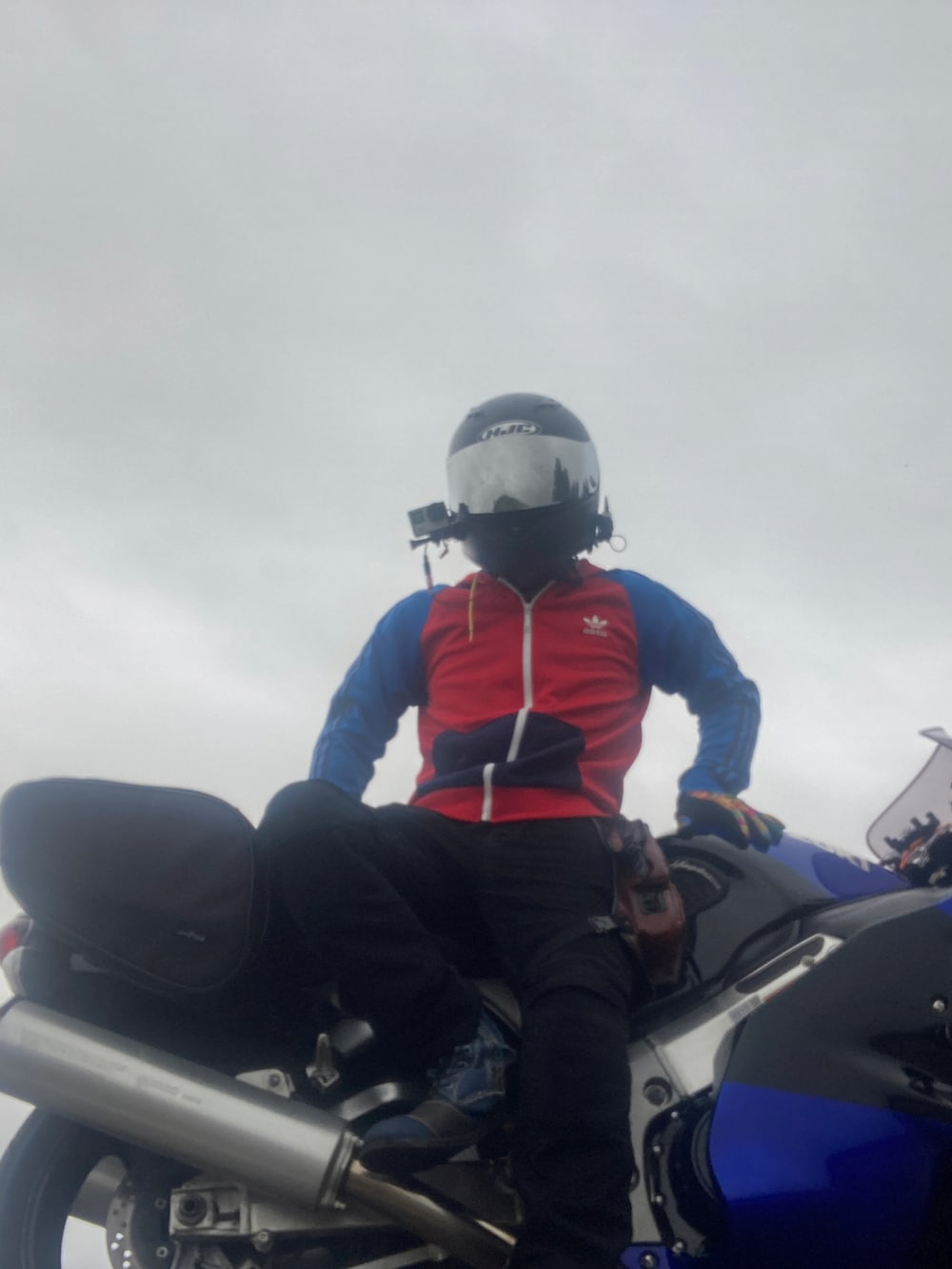 レッド系のパーカー、ブラック系のデニムパンツ、ブルー系のブーツを着用したメンズの秋コーディネートの2枚目の写真