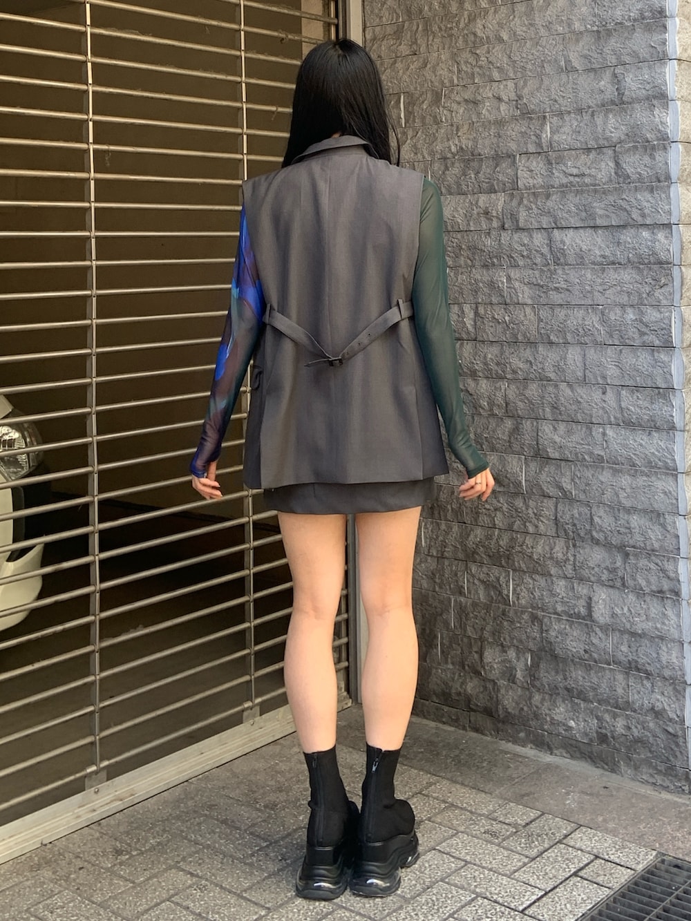 グレー系のベスト、グリーン系のTシャツ/カットソー、グレー系のスカートを着用したレディースの春コーディネートの4枚目の写真