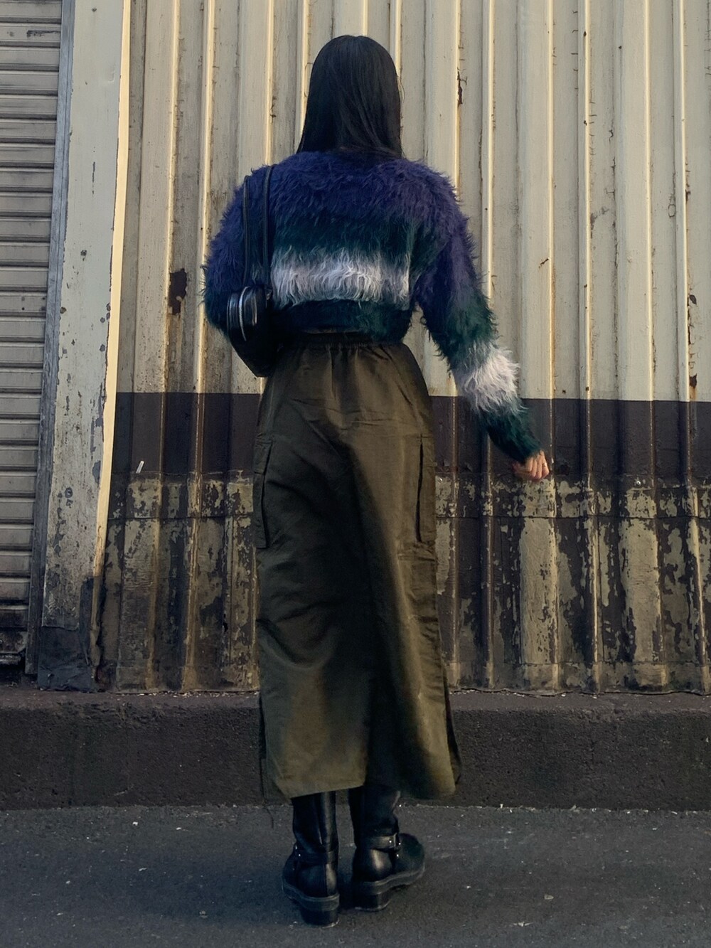 ブルー系のニット/セーター、ブラック系のボストンバッグ、グリーン系のスカートを着用したレディースの冬コーディネートの4枚目の写真