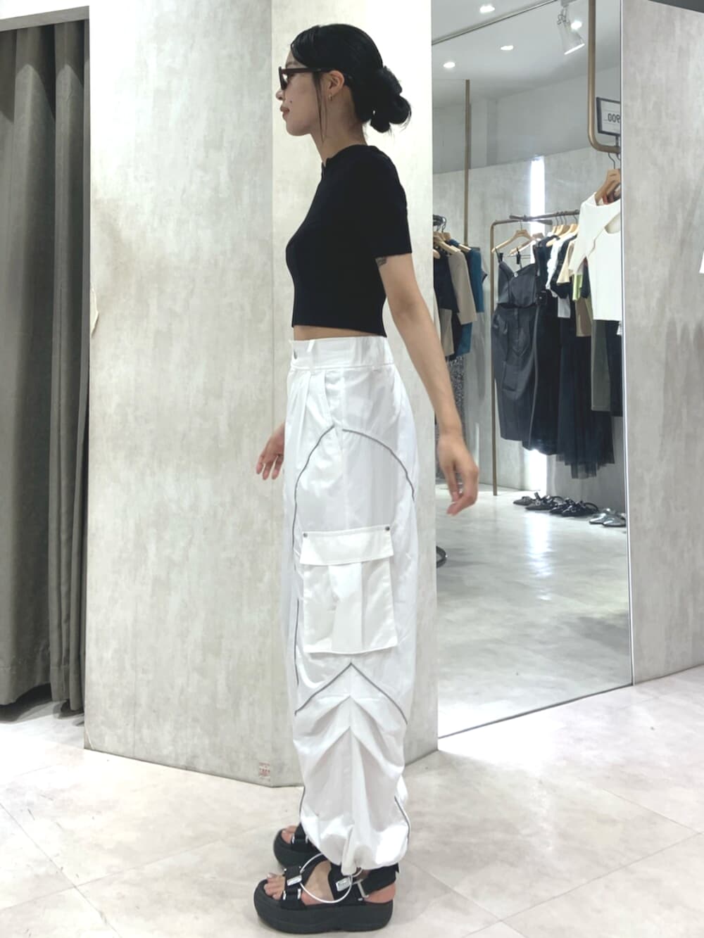 ブラック系のサンダル、ブラック系のニット/セーター、ホワイト系のカーゴパンツを着用したレディースの春コーディネートの3枚目の写真