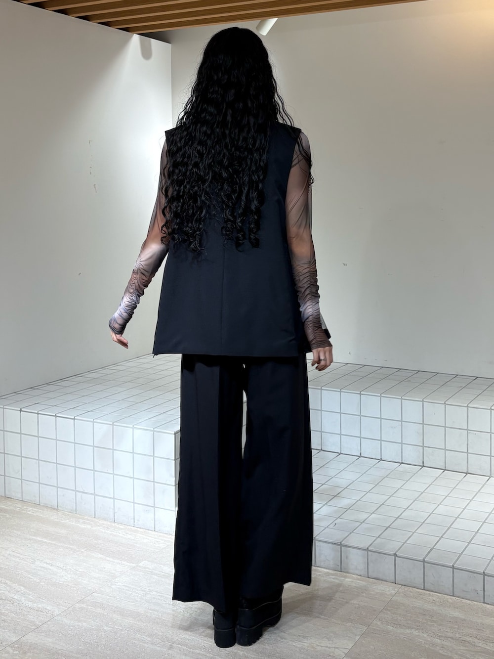 ブラック系のベスト、ブラック系のスラックス、ブラウン系のTシャツ/カットソーを着用したレディースの春コーディネートの3枚目の写真