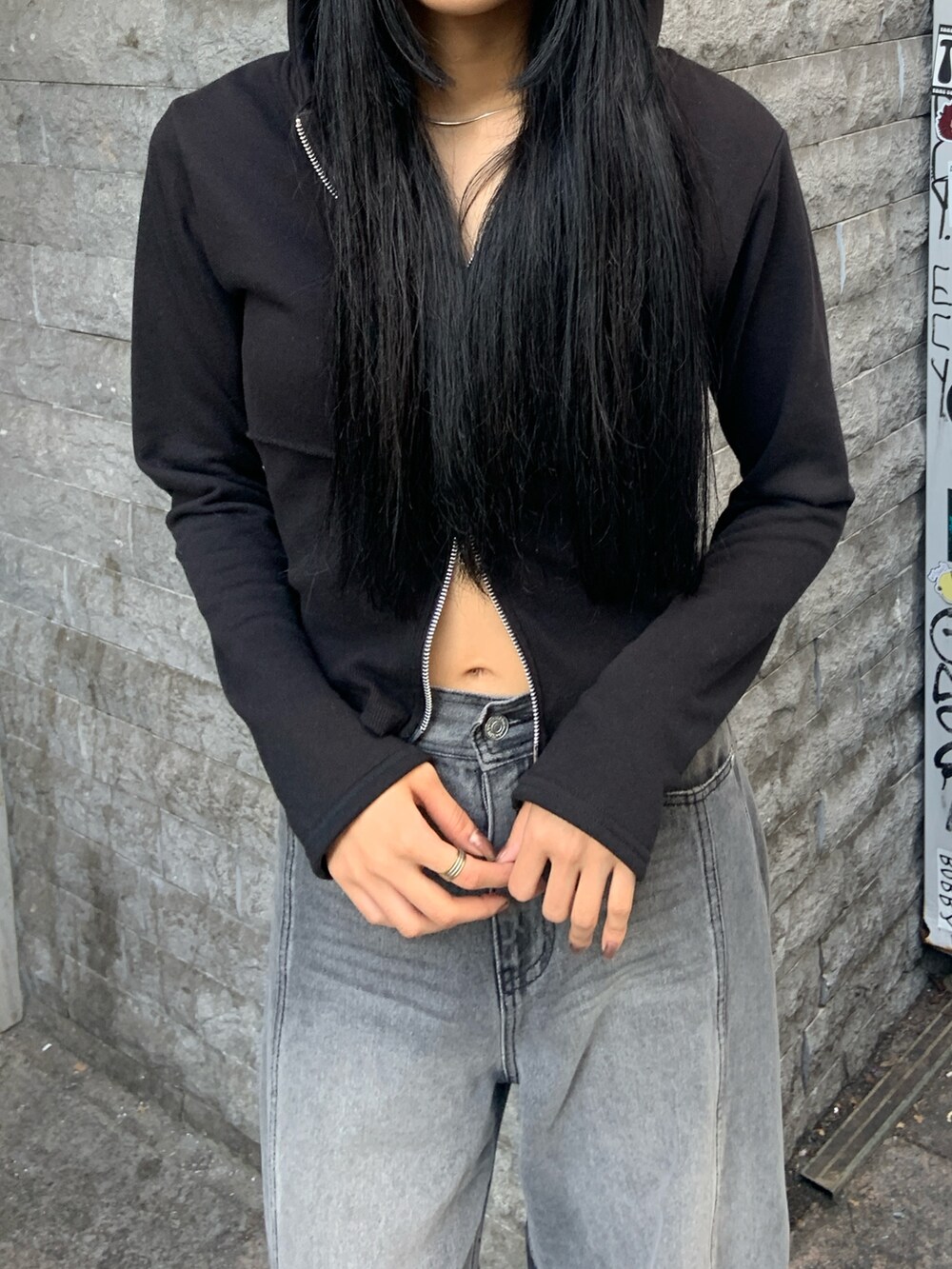 ブラック系のパーカー、ブラック系のデニムパンツ、ブラック系のブーツを着用したレディースの冬コーディネートの5枚目の写真