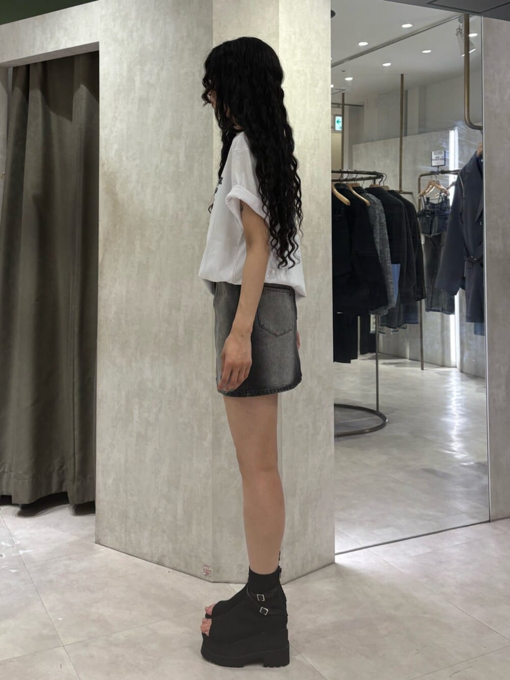 ブラック系のブーツ、ブラック系のデニムスカート、ホワイト系のTシャツ/カットソーを着用したレディースの春コーディネートの2枚目の写真