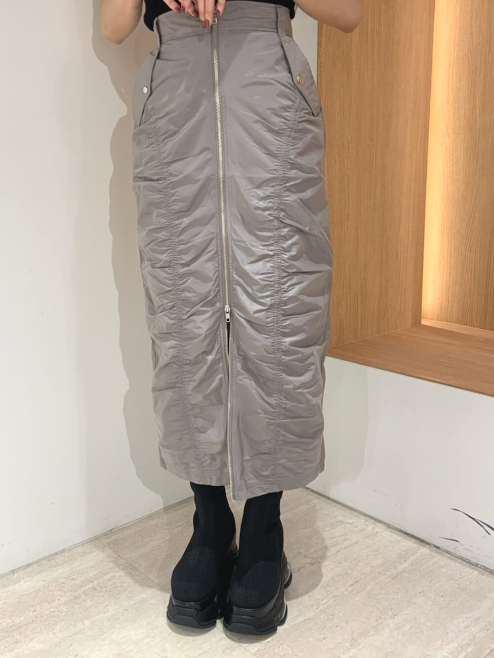 ブラック系のブーツ、ブラック系のニット/セーター、グレー系のスカートを着用したレディースの春コーディネートの6枚目の写真