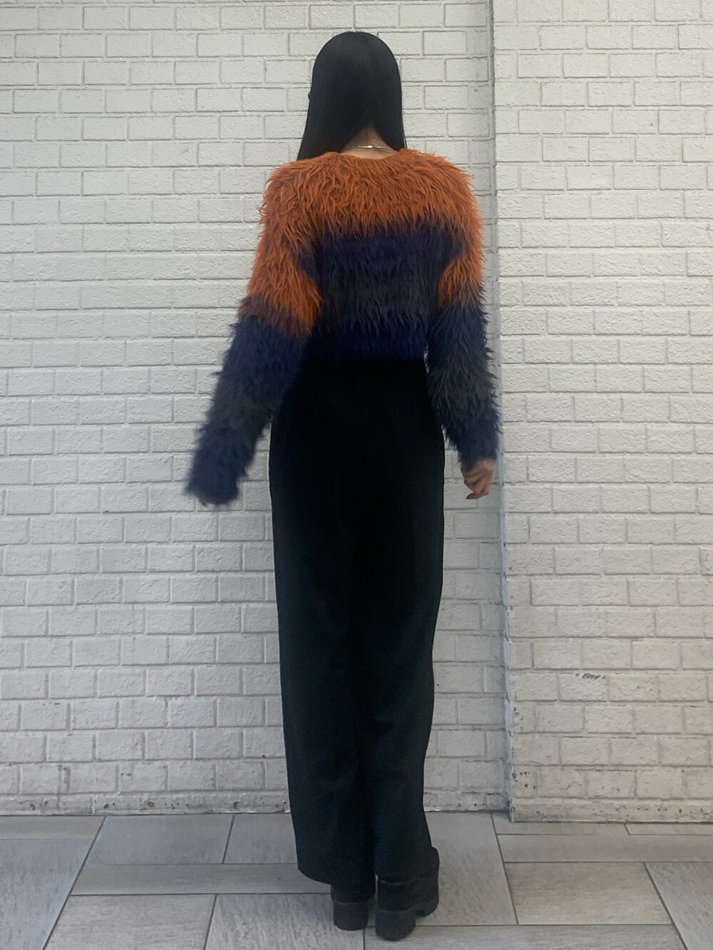 オレンジ系のニット/セーター、ブラック系のその他パンツ、ブラック系のブーツを着用したレディースの秋コーディネートの3枚目の写真