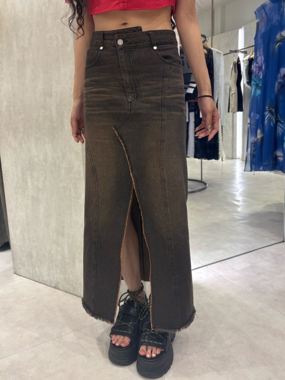 レッド系のシャツ/ブラウス、ブラック系のサンダル、ブラウン系のデニムスカートを着用したレディースの夏コーディネートの5枚目の写真