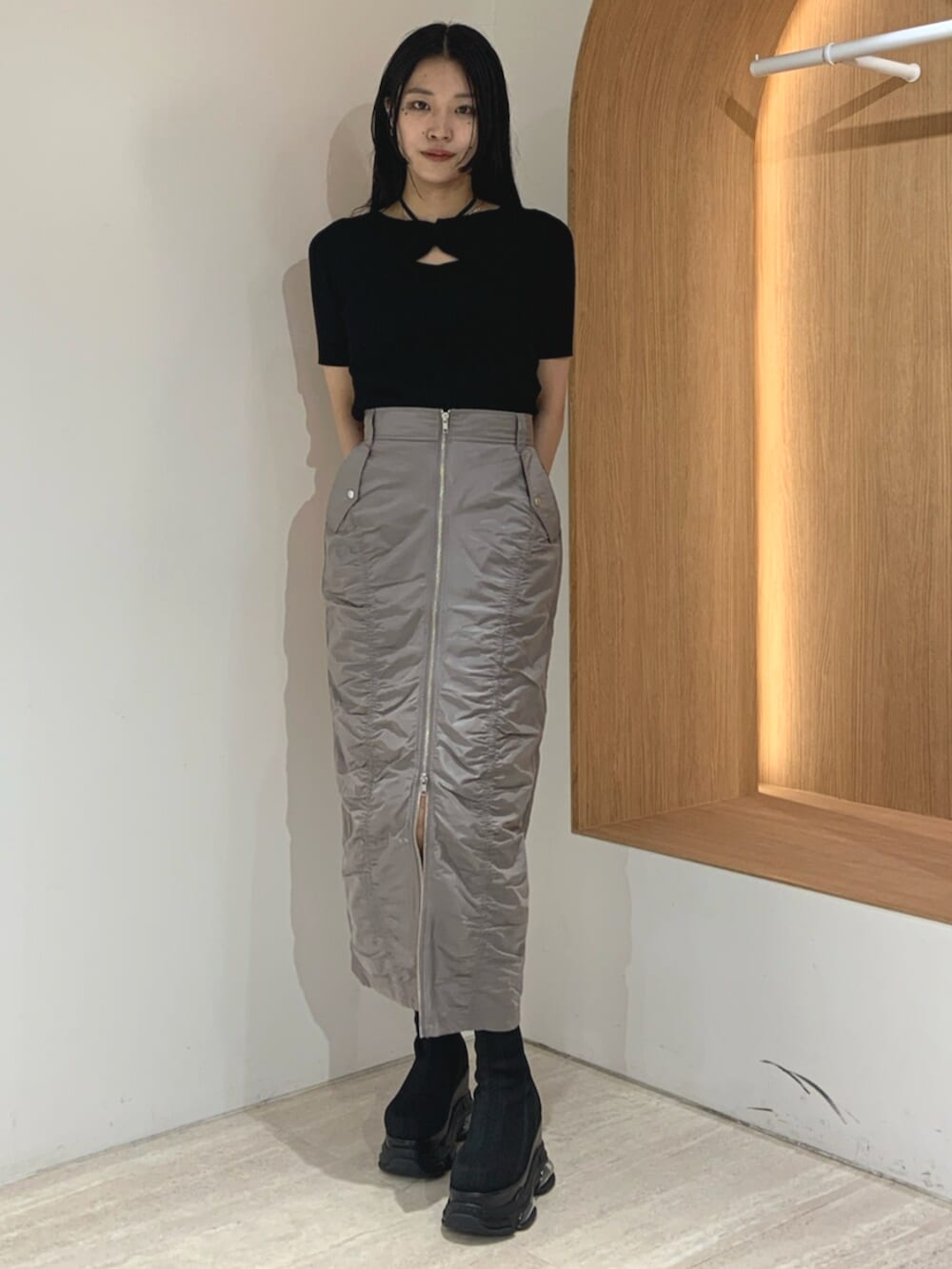 ブラック系のブーツ、ブラック系のニット/セーター、グレー系のスカートを着用したレディースの春コーディネートの2枚目の写真