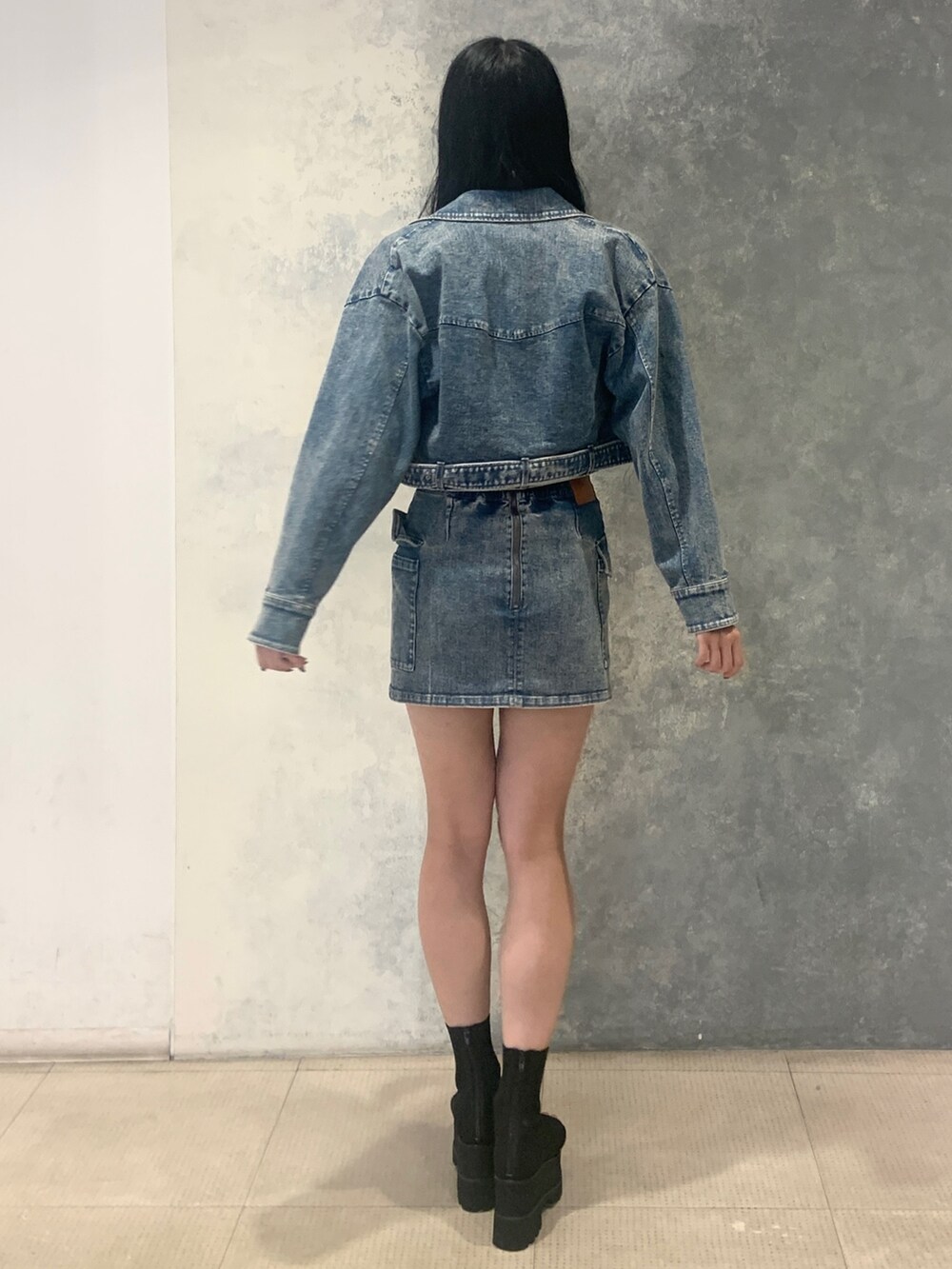 ブルー系のスカート、ブラック系のブーツ、ブルー系のデニムジャケットを着用したレディースの夏コーディネートの3枚目の写真