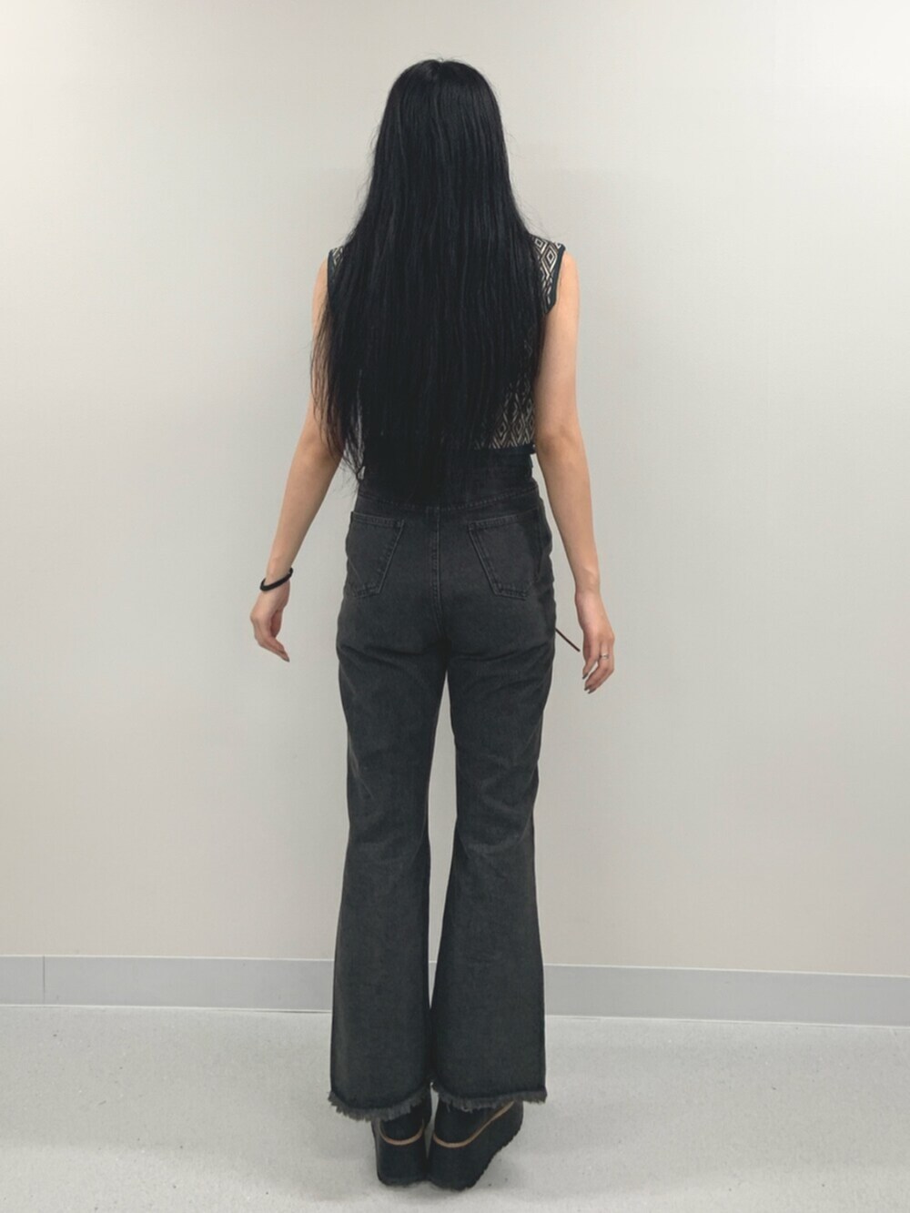 ブラック系のデニムパンツ、ブラック系のブーツ、グリーン系のタンクトップを着用したレディースの夏コーディネートの4枚目の写真