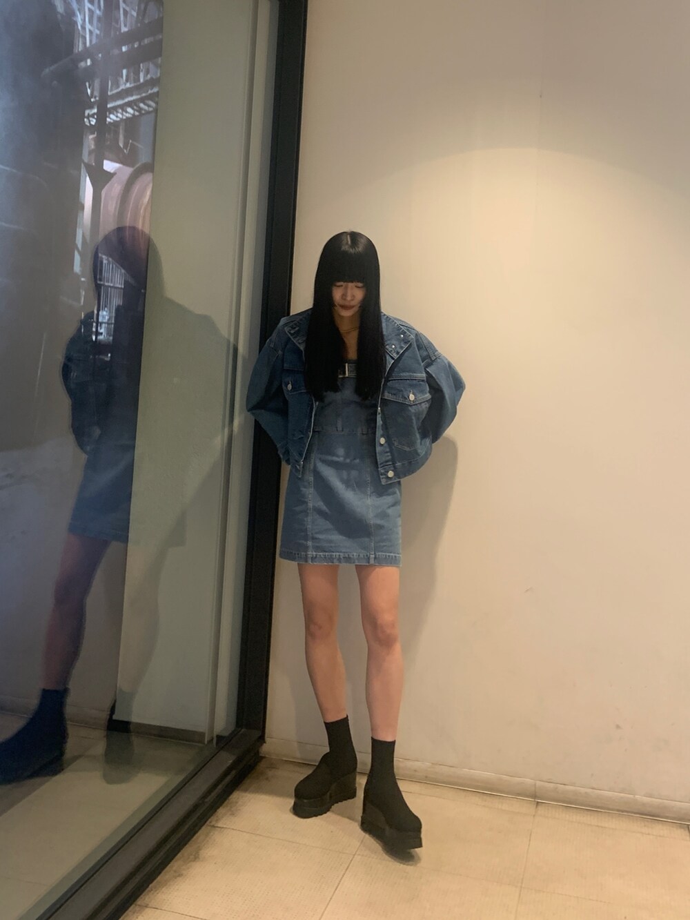 ブルー系のデニムジャケット、ブルー系のワンピース、ブラック系のブーツを着用したレディースの冬コーディネートの2枚目の写真