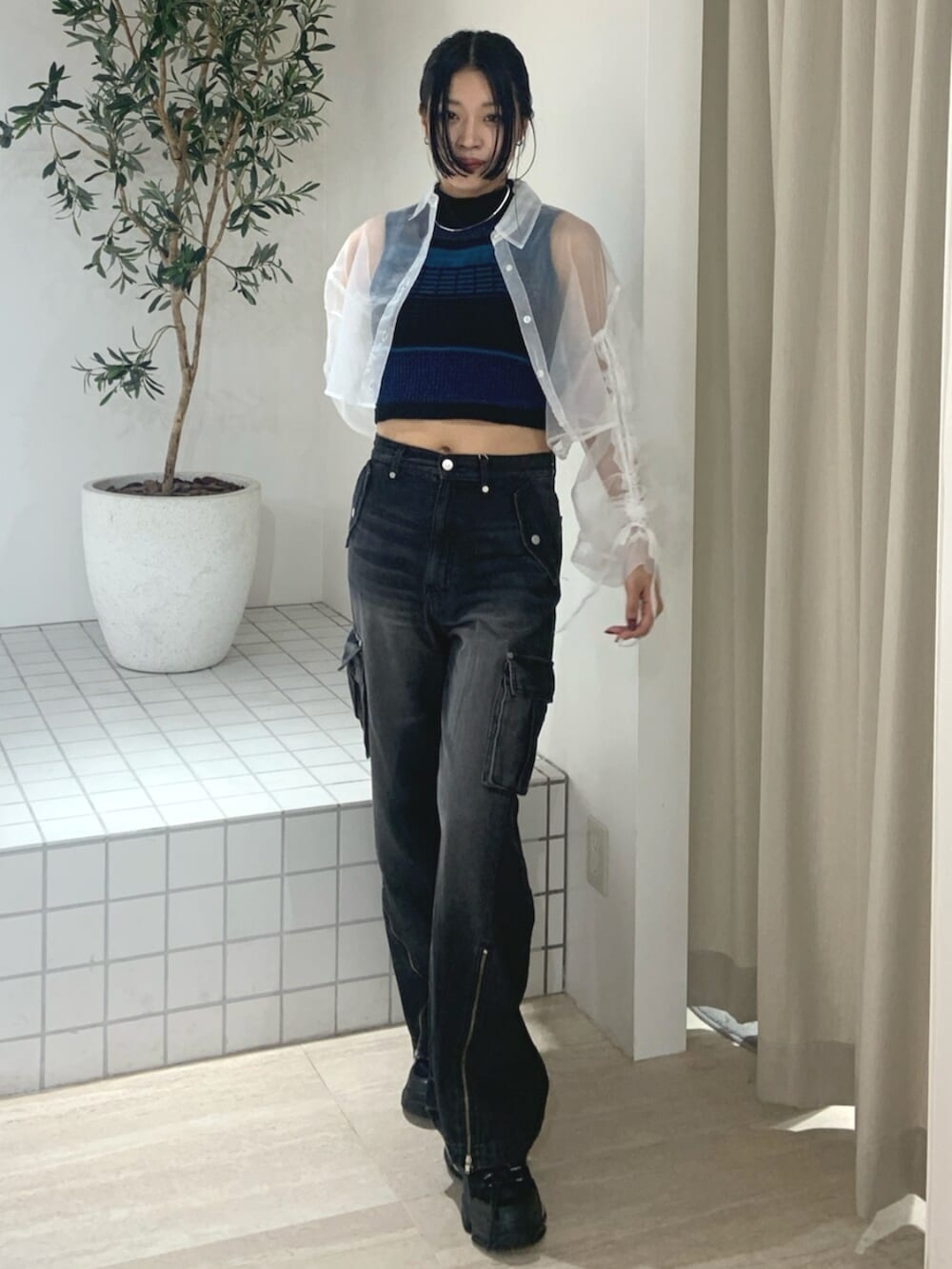 ブラック系のデニムパンツ、ブラック系のスニーカー、ホワイト系のシャツ/ブラウスを着用したレディースの春コーディネートの2枚目の写真