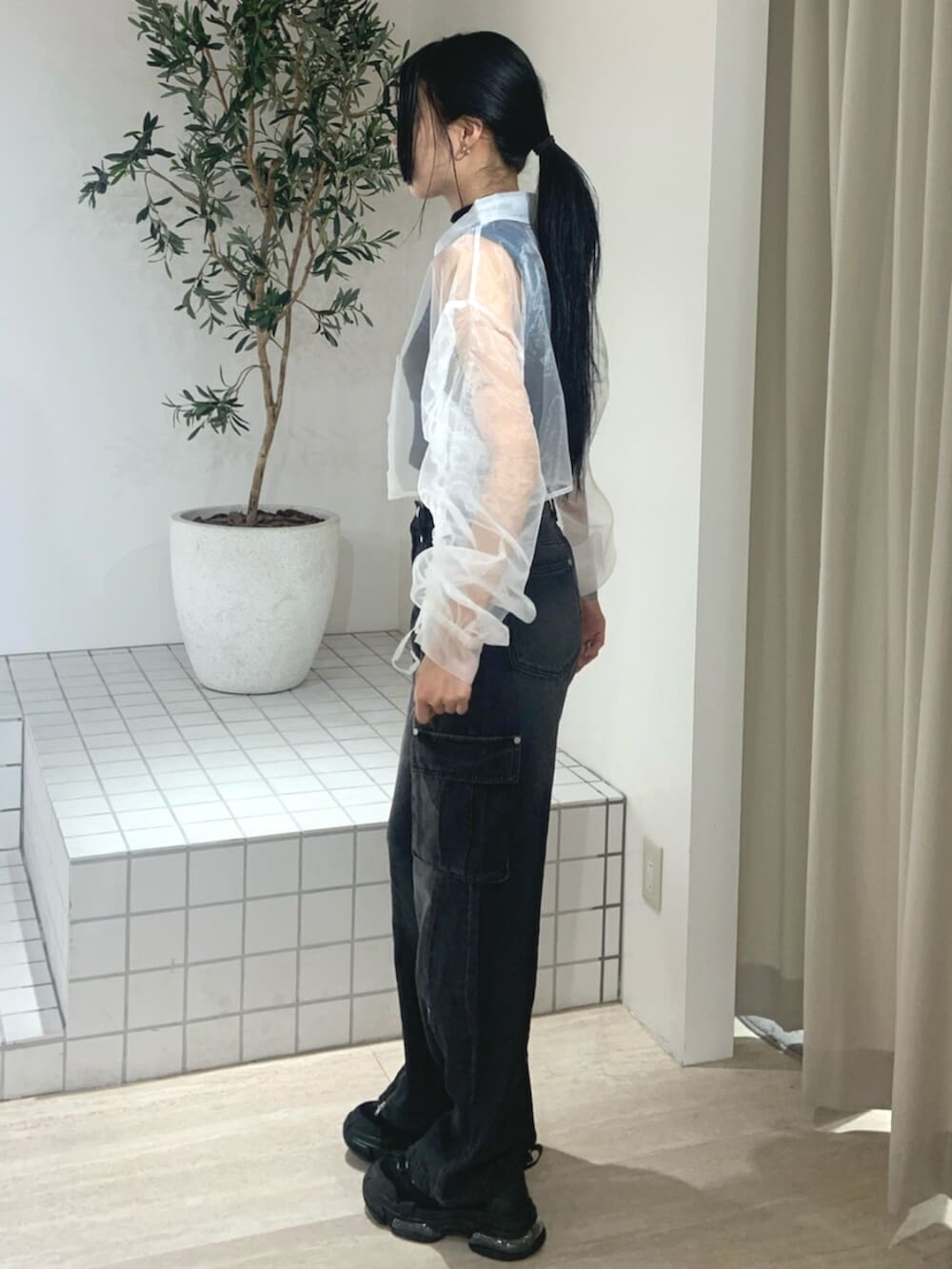 ブラック系のデニムパンツ、ブラック系のスニーカー、ホワイト系のシャツ/ブラウスを着用したレディースの春コーディネートの3枚目の写真