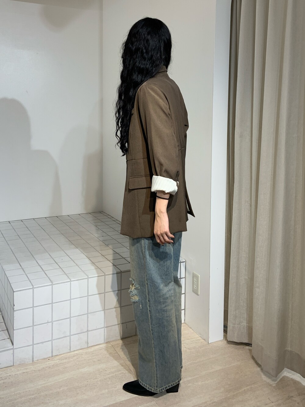 ブラウン系のブーツ、ブルー系のデニムパンツ、ブラウン系のテーラードジャケットを着用したレディースの秋コーディネートの2枚目の写真