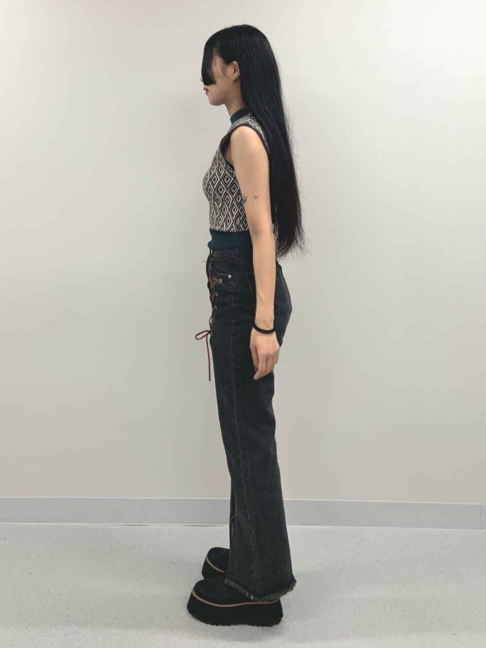 ブラック系のデニムパンツ、ブラック系のブーツ、グリーン系のタンクトップを着用したレディースの夏コーディネートの3枚目の写真