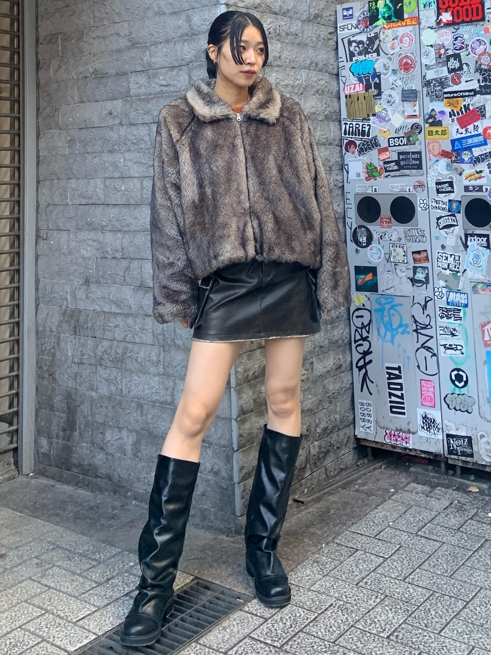 グレー系のブルゾン、ブラウン系のスカート、ブラック系のブーツを着用したレディースの冬コーディネートの2枚目の写真